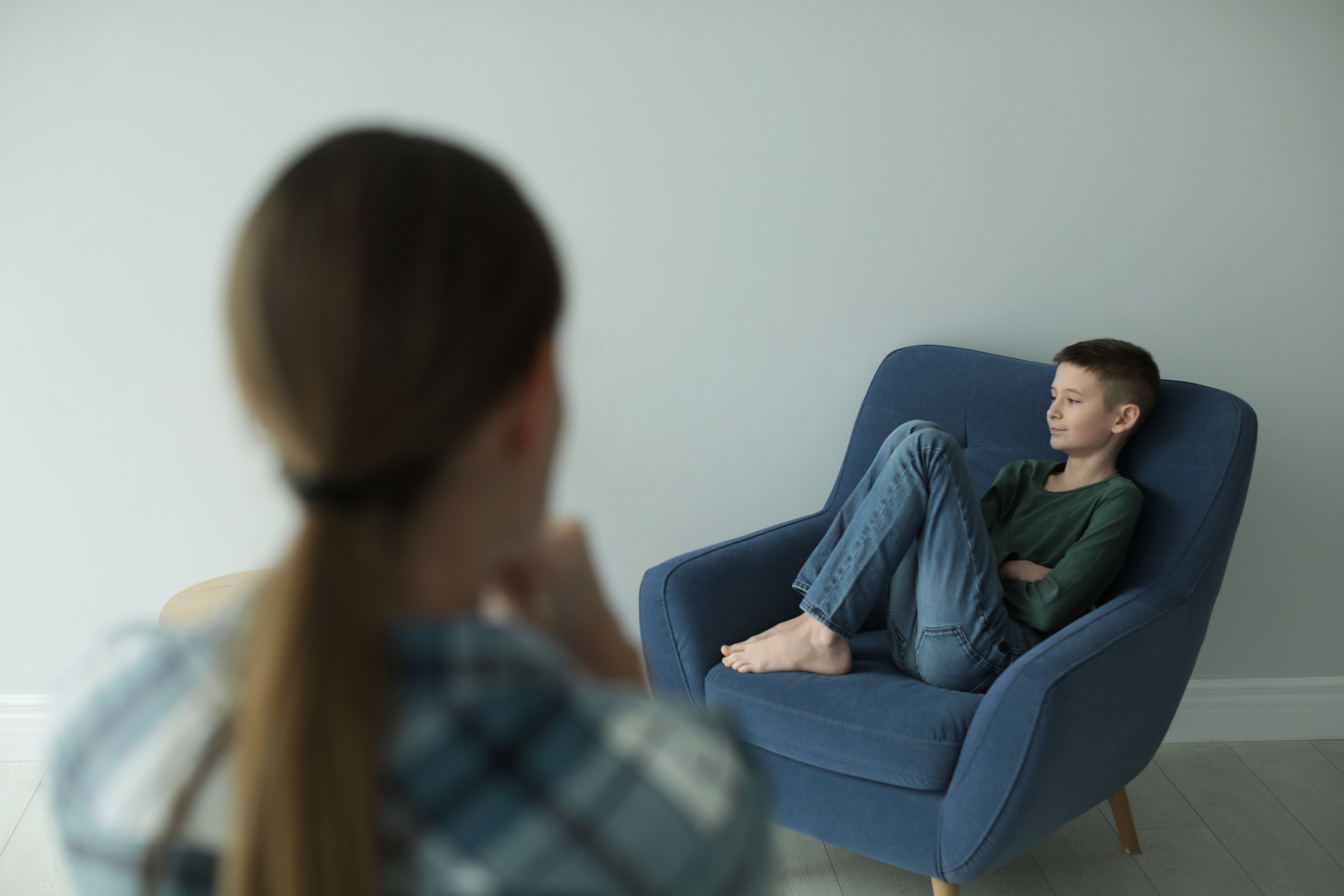 Un niño sentado en una silla mientras una mujer mira | Foto: Shutterstock