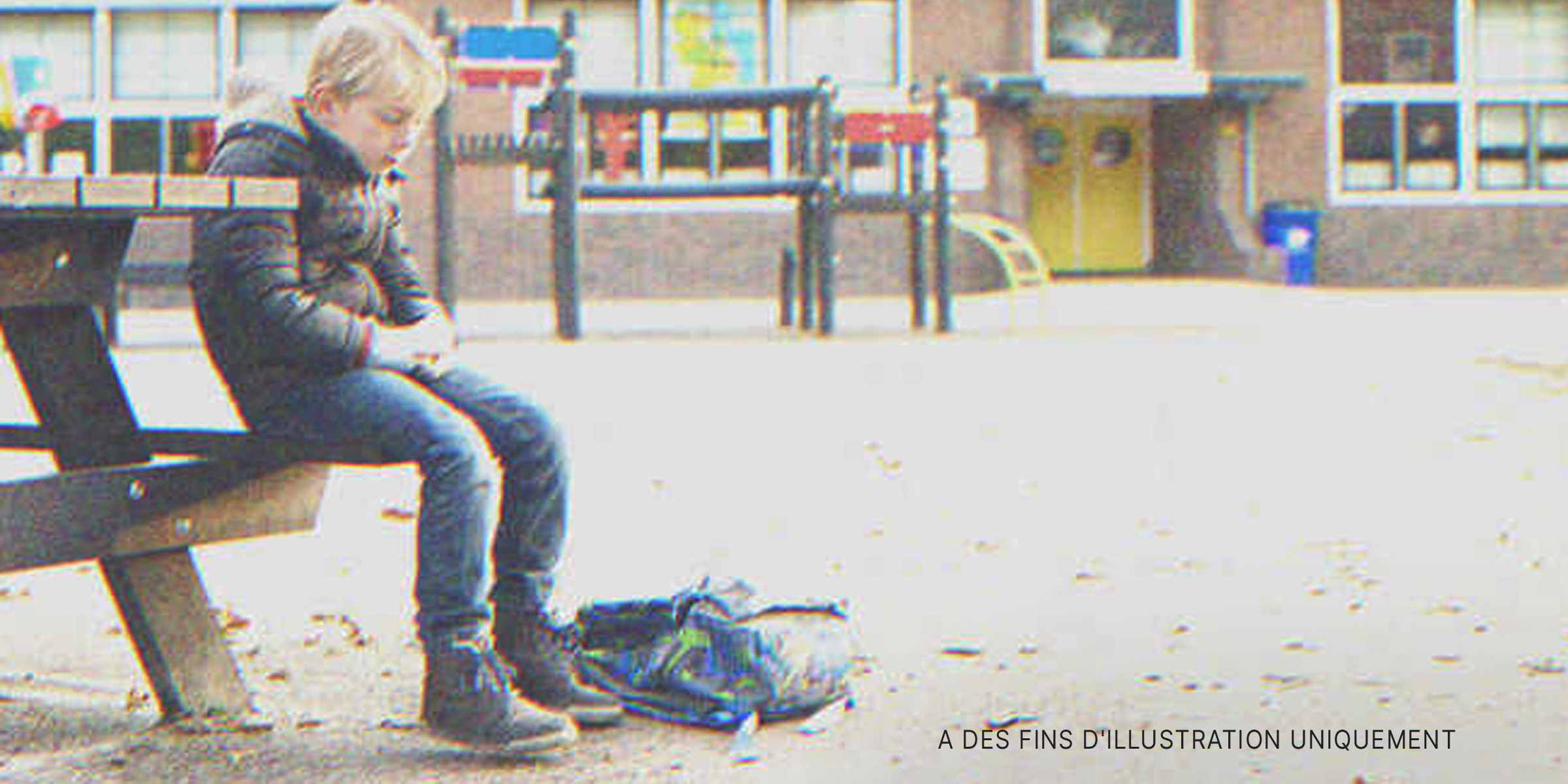 Un garçon assis seul sur un banc à l'extérieur d'une école | Source : Shutterstock