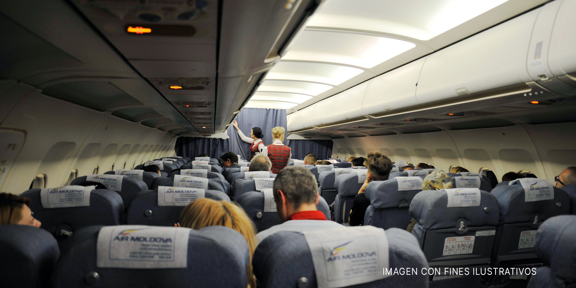 Interior de un avión con pasajeros sentados y auxiliares de vuelo. | Foto: Shutterstock