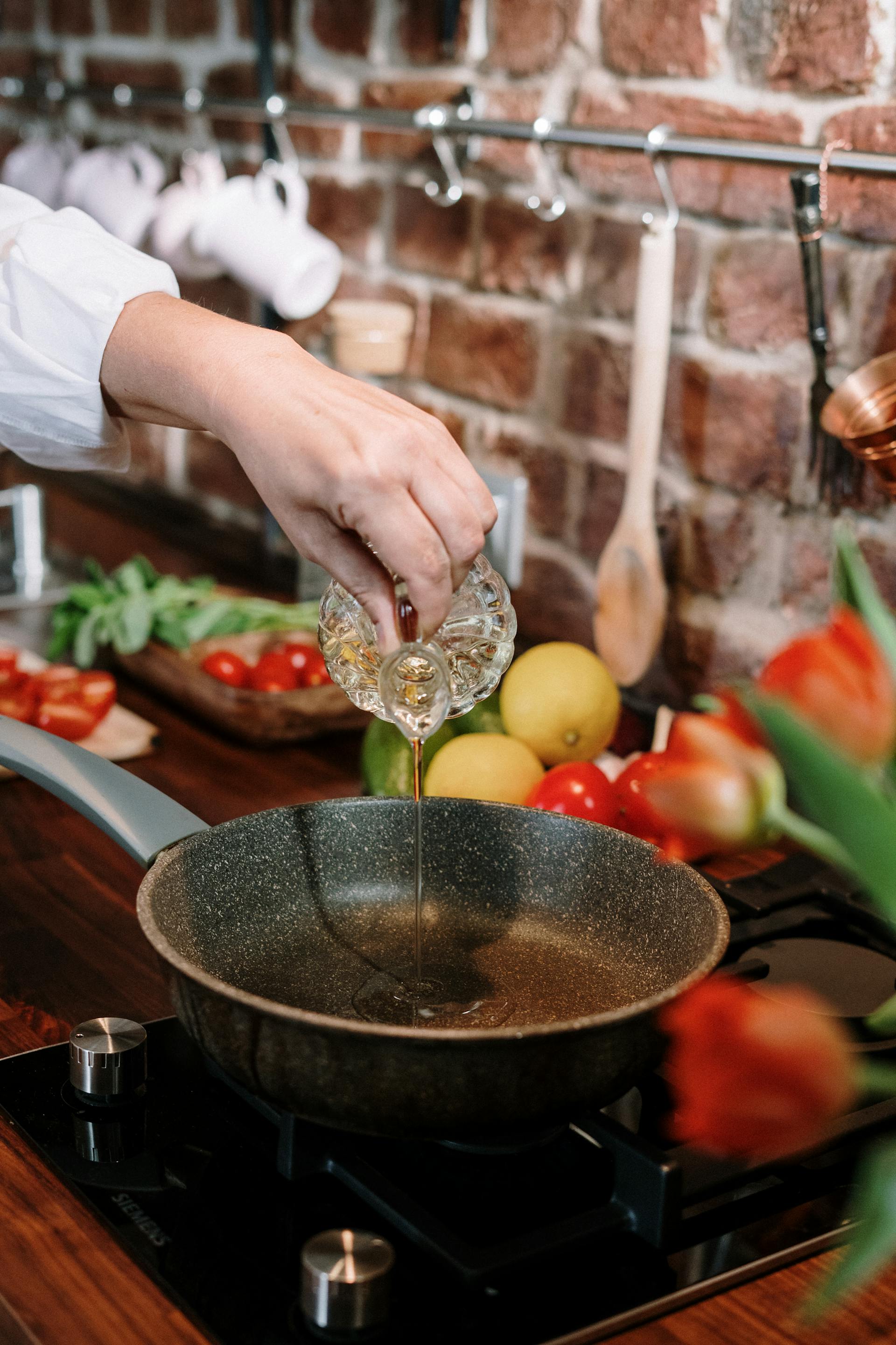 Una mujer vierte aceite en una sartén | Fuente: Pexels