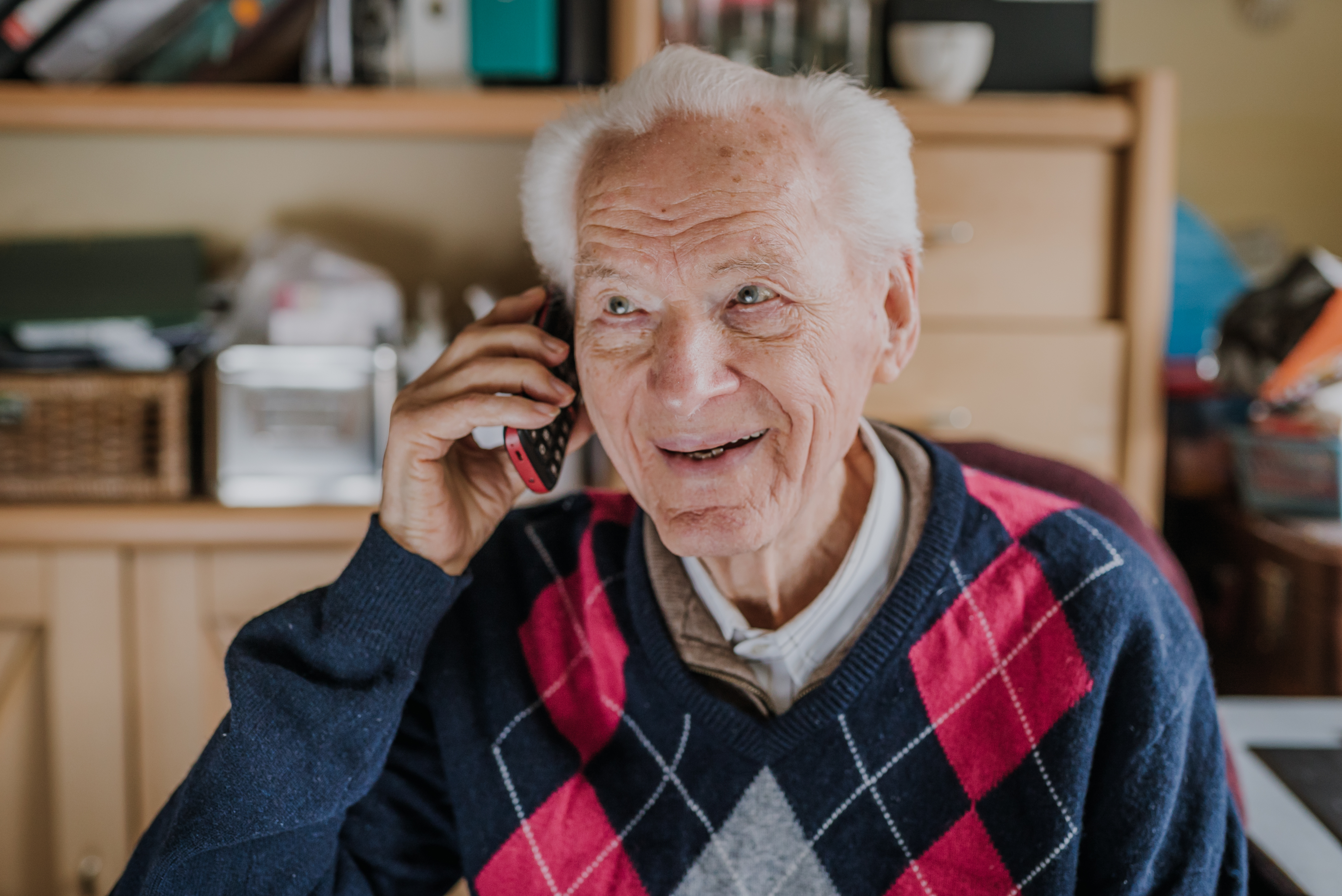 Un hombre sonríe mientras habla por teléfono | Fuente: Getty Images