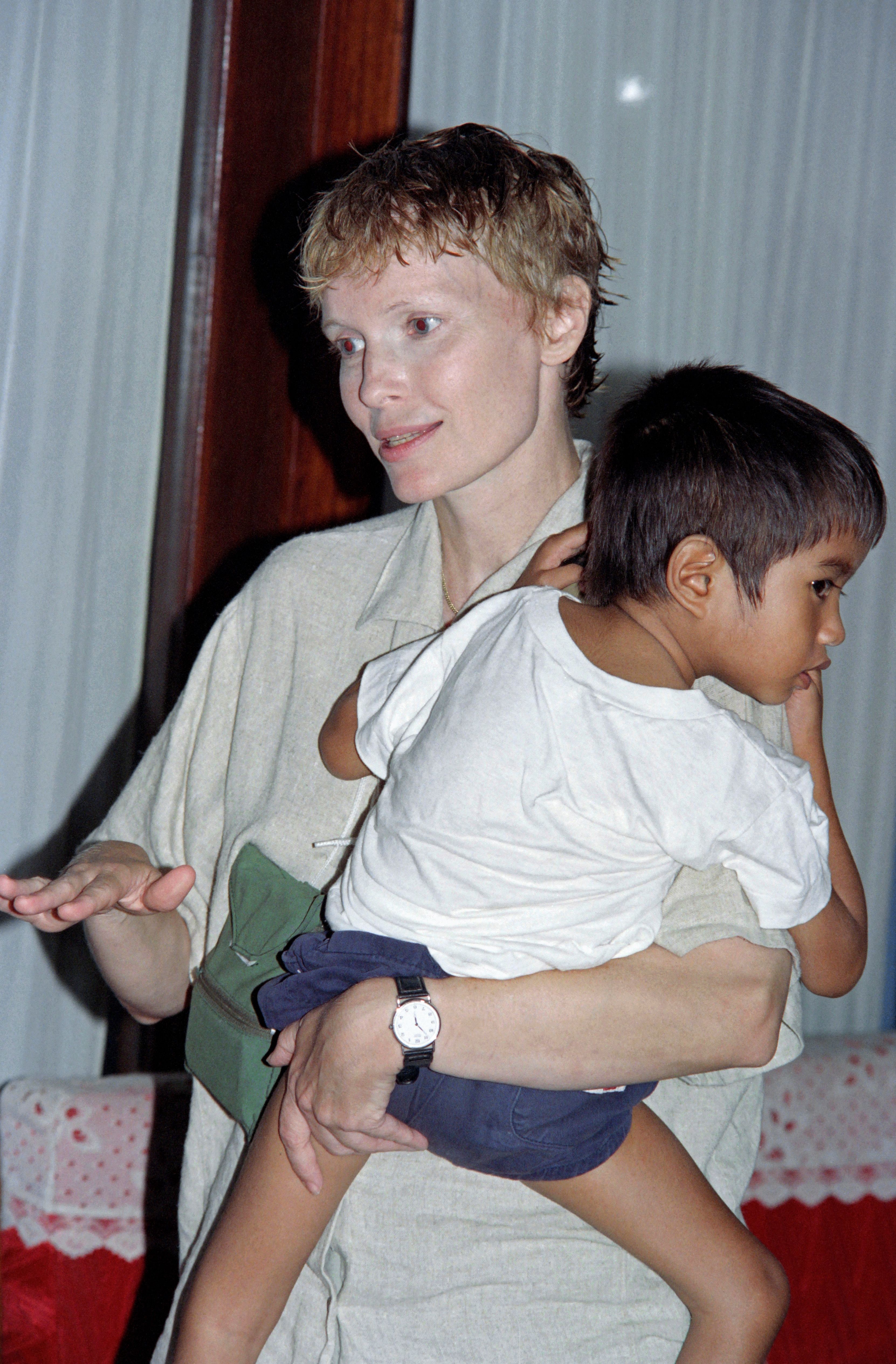 Mia Farrow con Sanjay Farrow en brazos mientras pasaba una semana en Hanoi para adoptar al niño de cinco años, el 24 de septiembre de 1991. | Fuente: Getty Images