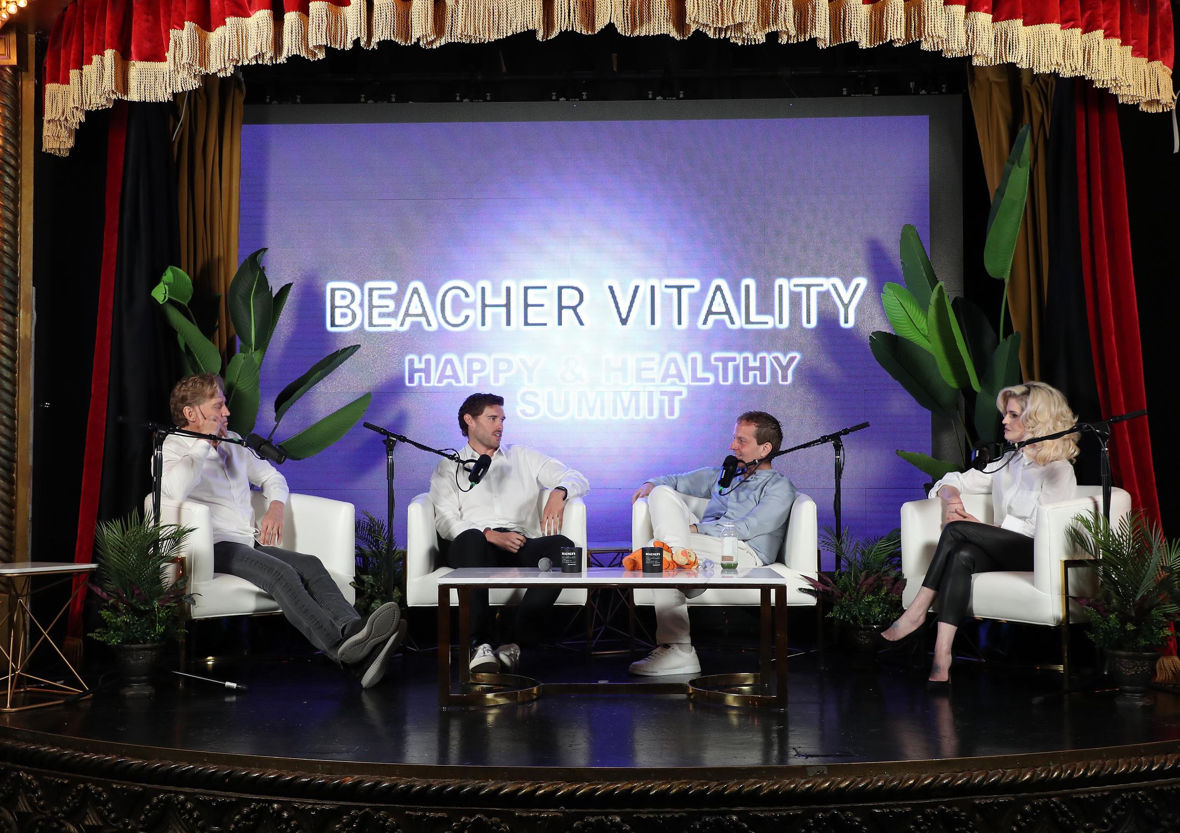 Christopher Schwarzenegger aparece en la Cumbre Beacher Vitality Happy & Healthy el 10 de mayo de 2025. Sentado junto al Dr. Robert Huizenga, Jeff Beacher y Kelly Osbourne, participa en una conversación centrada en la salud y la transformación, vestido con una impecable camisa blanca y pantalones negros.
