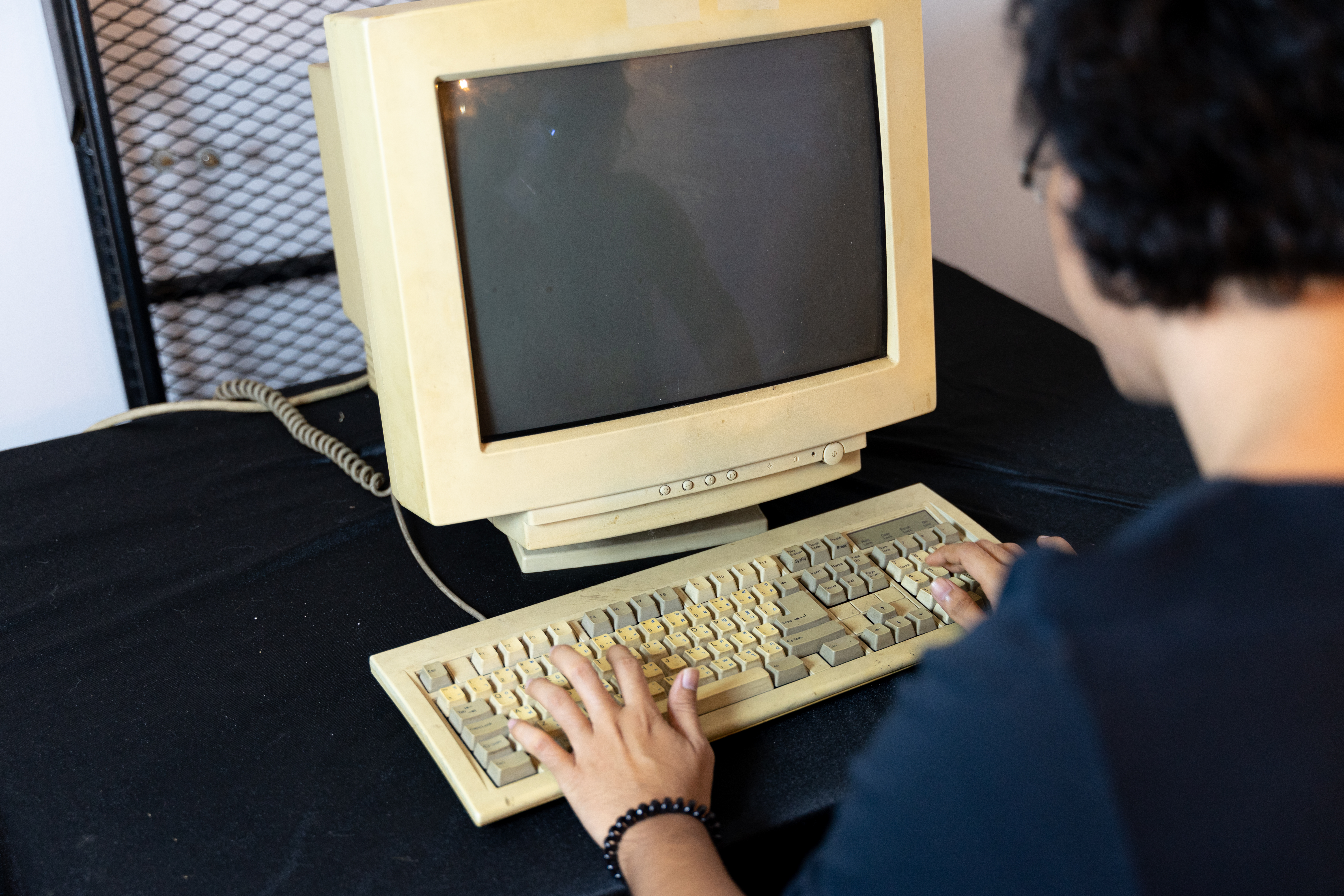 Antiguo ordenador personal con un hombre tecleando el código | Fuente: Shutterstock.com