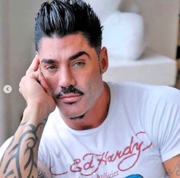 Un primer plano de Ricardo Fort apoyando su rostro sobre la mano derecha mientras lucía una remera blanca de la marca Ed Hardy. En la postal destacan su peinado con jopo hacia arriba, bigote y barba candado recortados, y los elaborados tatuajes tribales que cubrían su brazo. | Fuente: Instagram/felipe_fort_