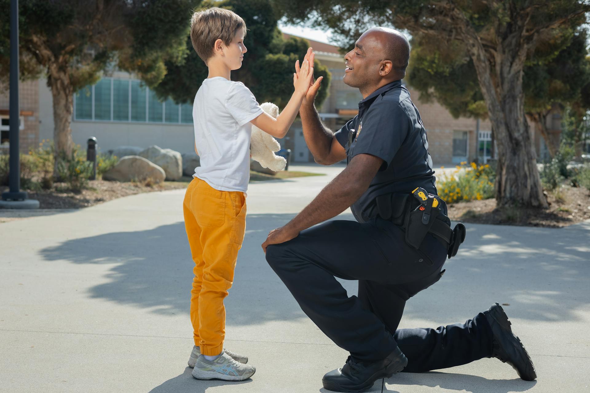 Un policía chocando los cinco con un niño | Fuente: Pexels