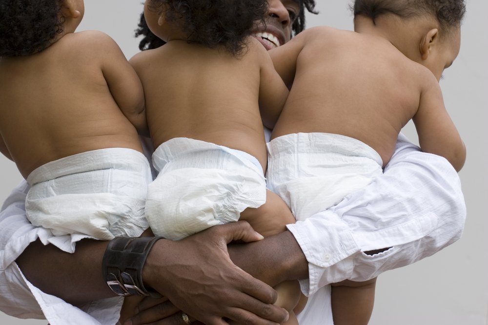 Hombre cargando a tres bebes. | Foto: Shutterstock