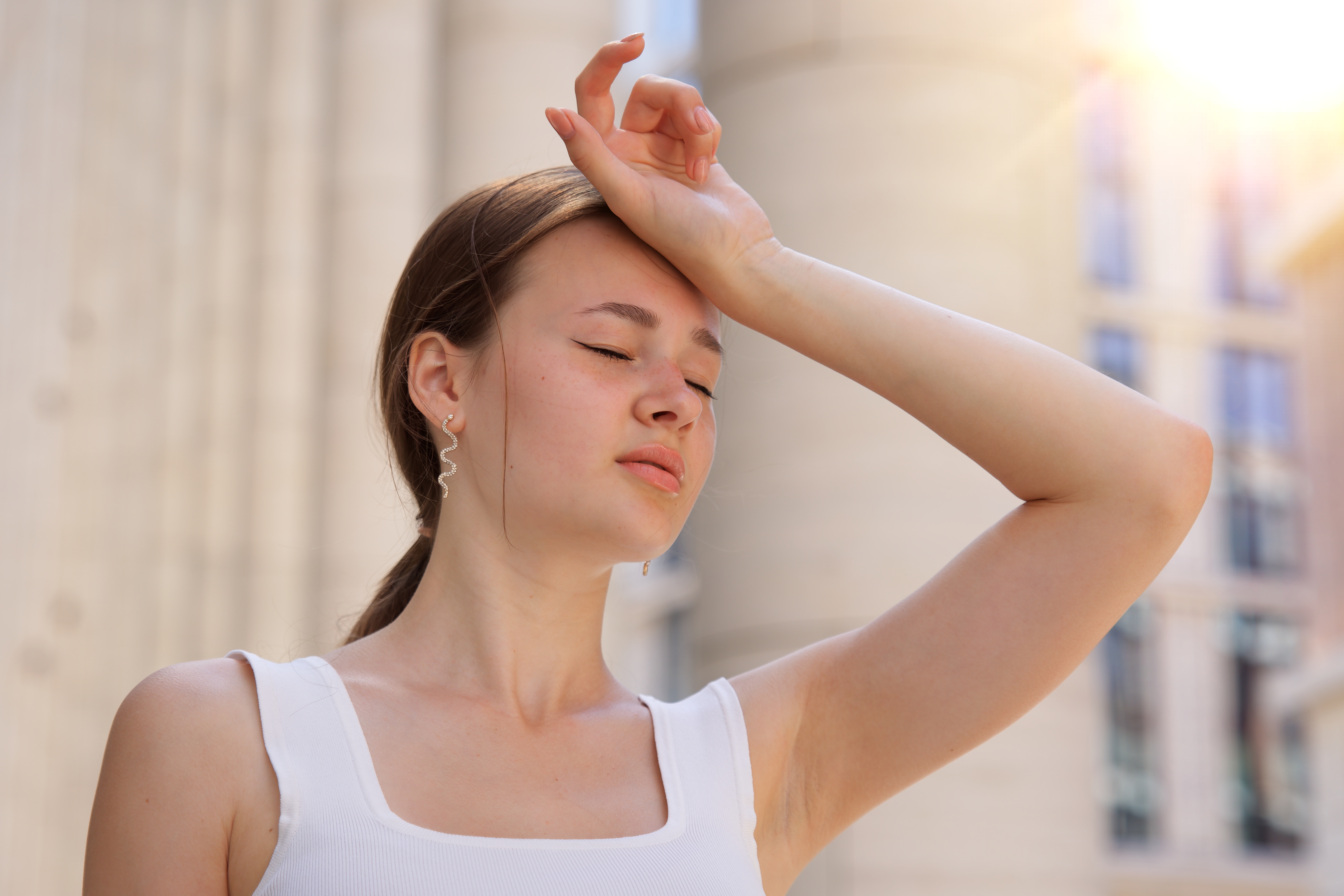 Chica joven con la mano en la cabeza mirando mareada | Fuente: Shutterstock
