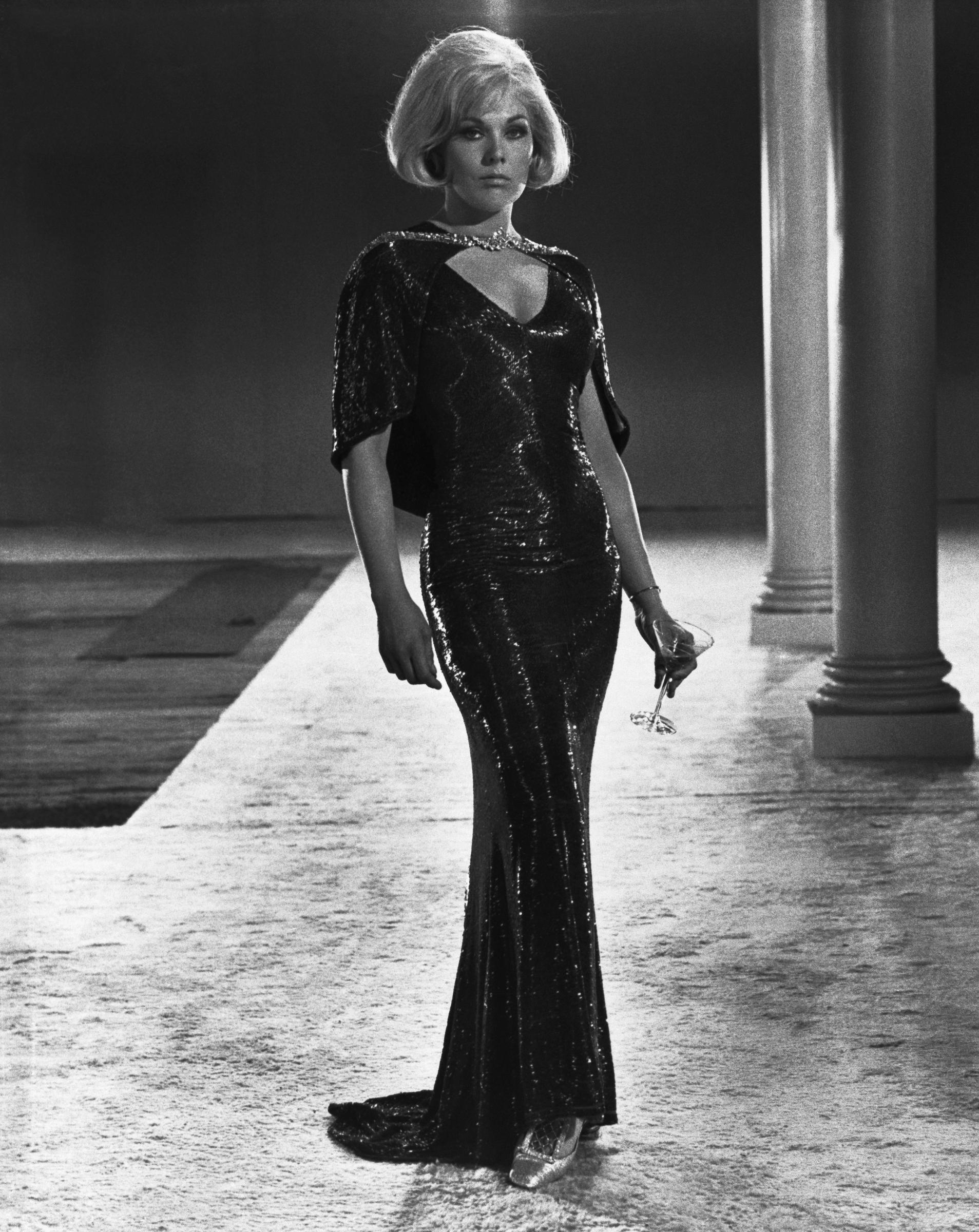 Kim Novak luce un deslumbrante vestido de noche negro con una capa a juego en una escena de The Legend of Lylah Clare. | Fuente: Getty Images