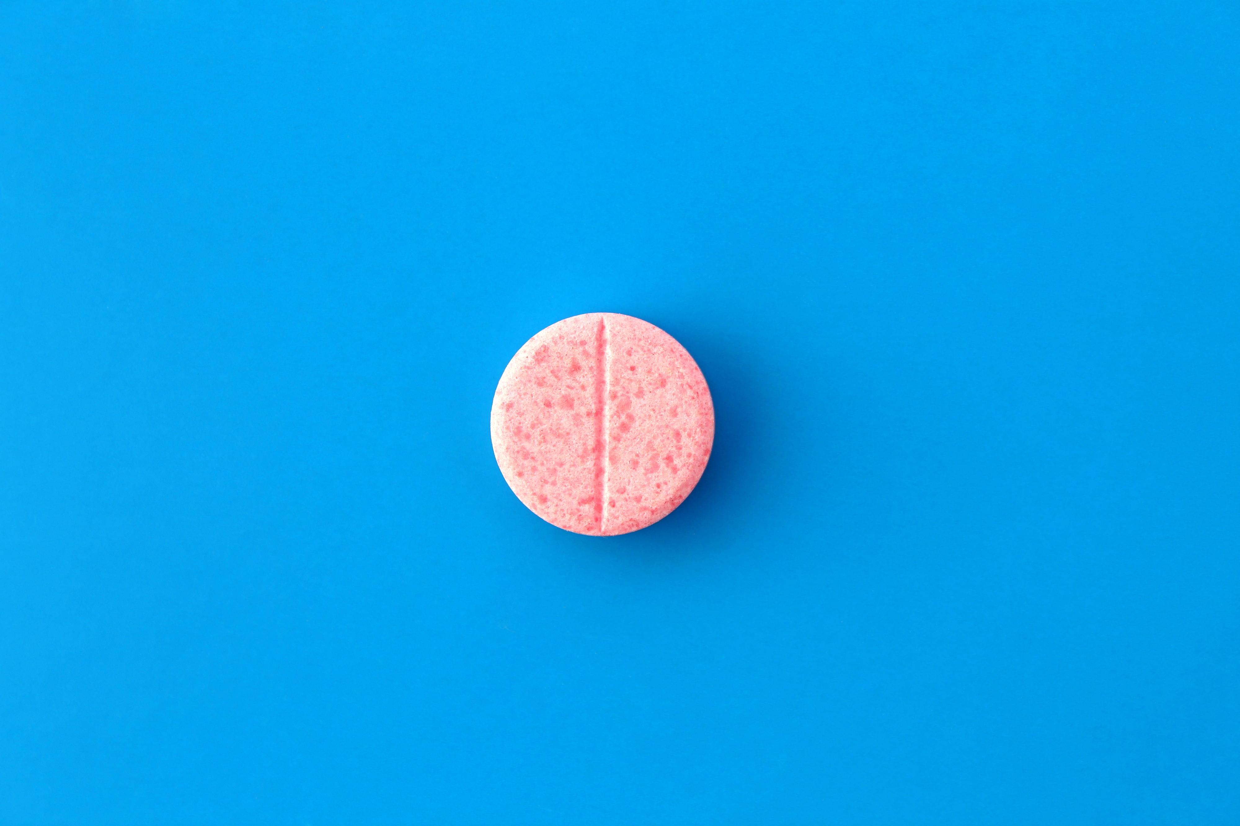 Una píldora rosa sobre fondo azul. | Fuente: Shutterstock