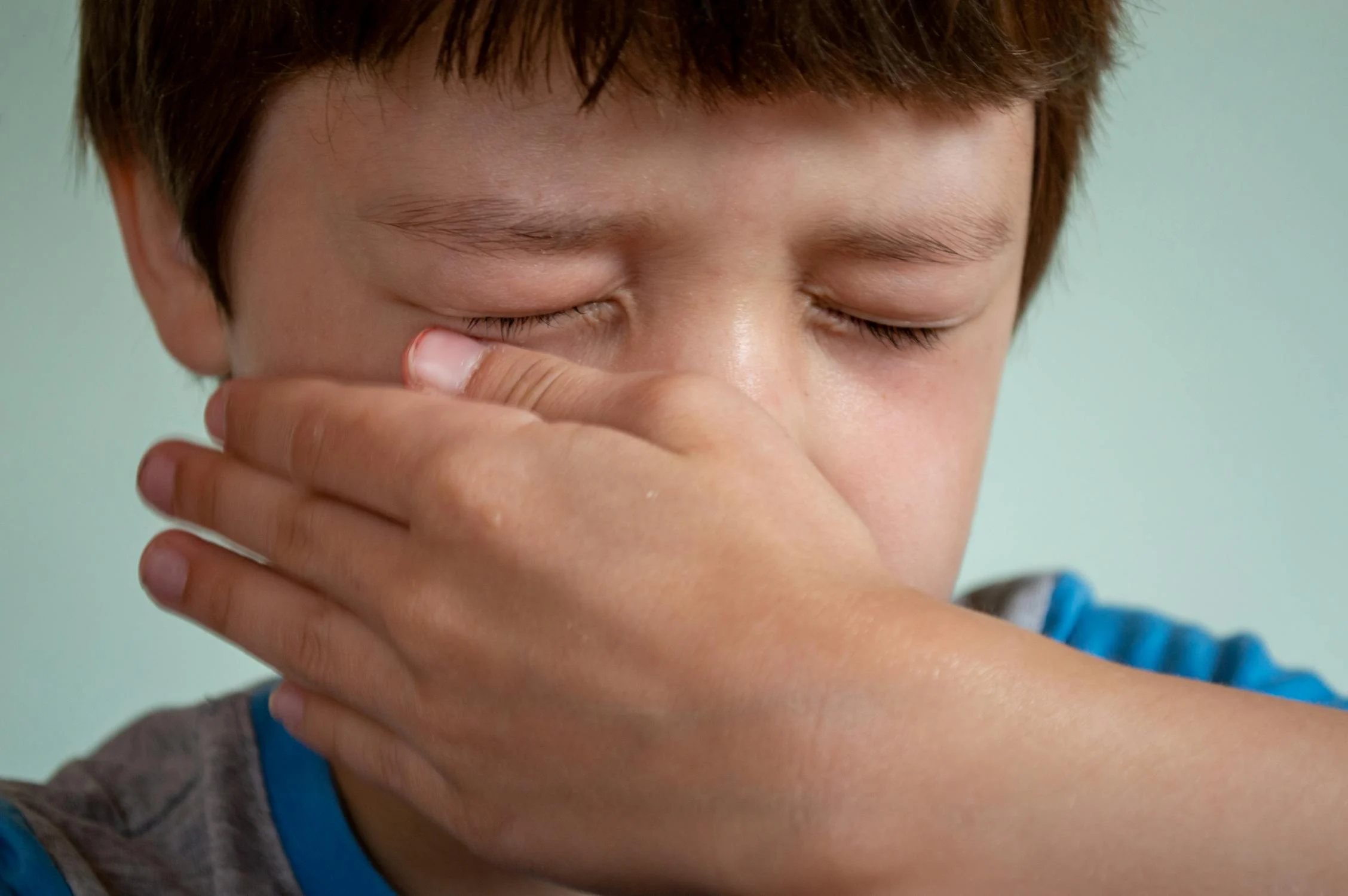 Un niño triste limpiándose la cara | Fuente: Pexels