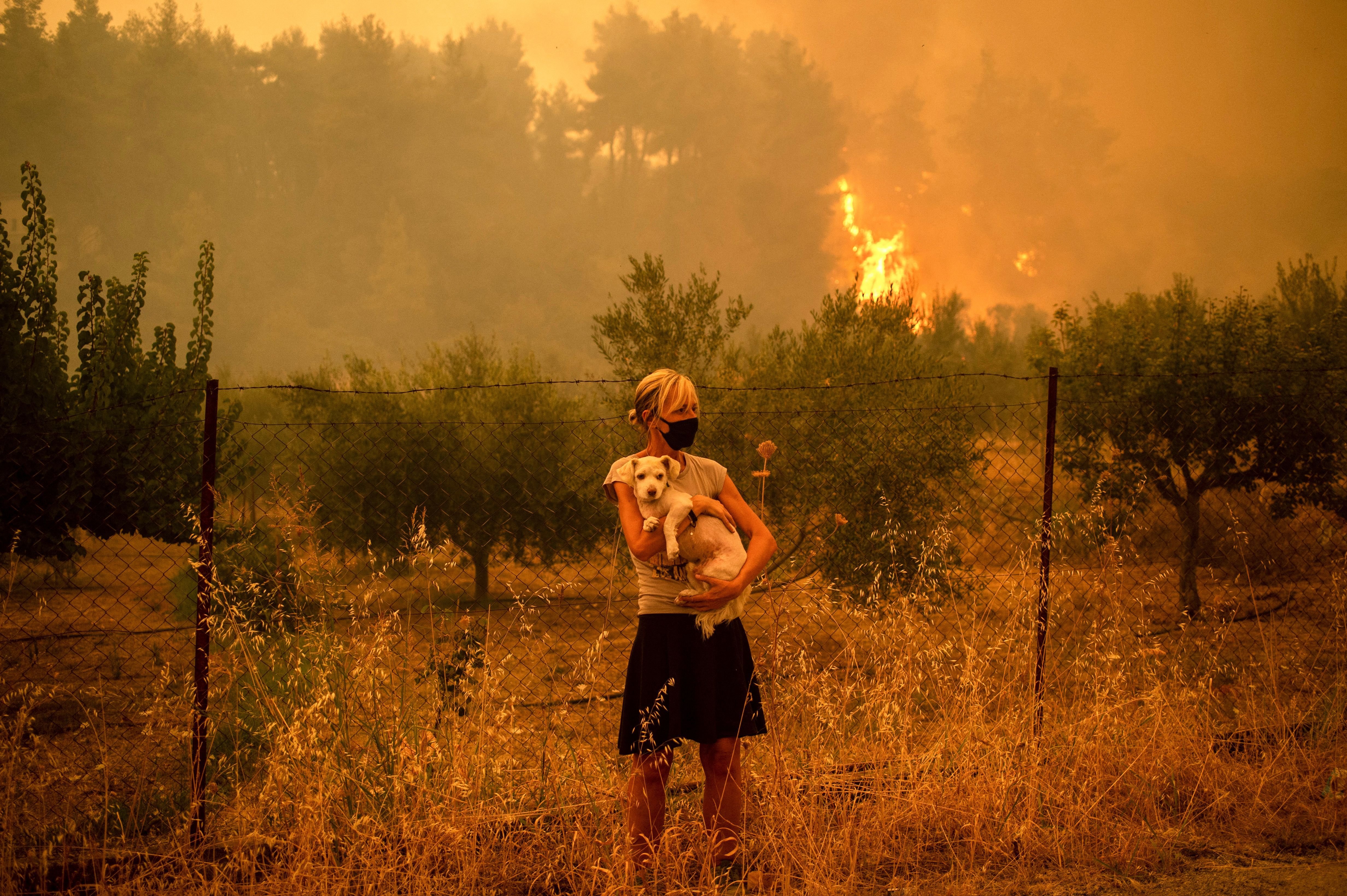 Mujer sostiene a perrito en Grecia durante incendio forestal en agosto de 2021. | Foto: Getty Images