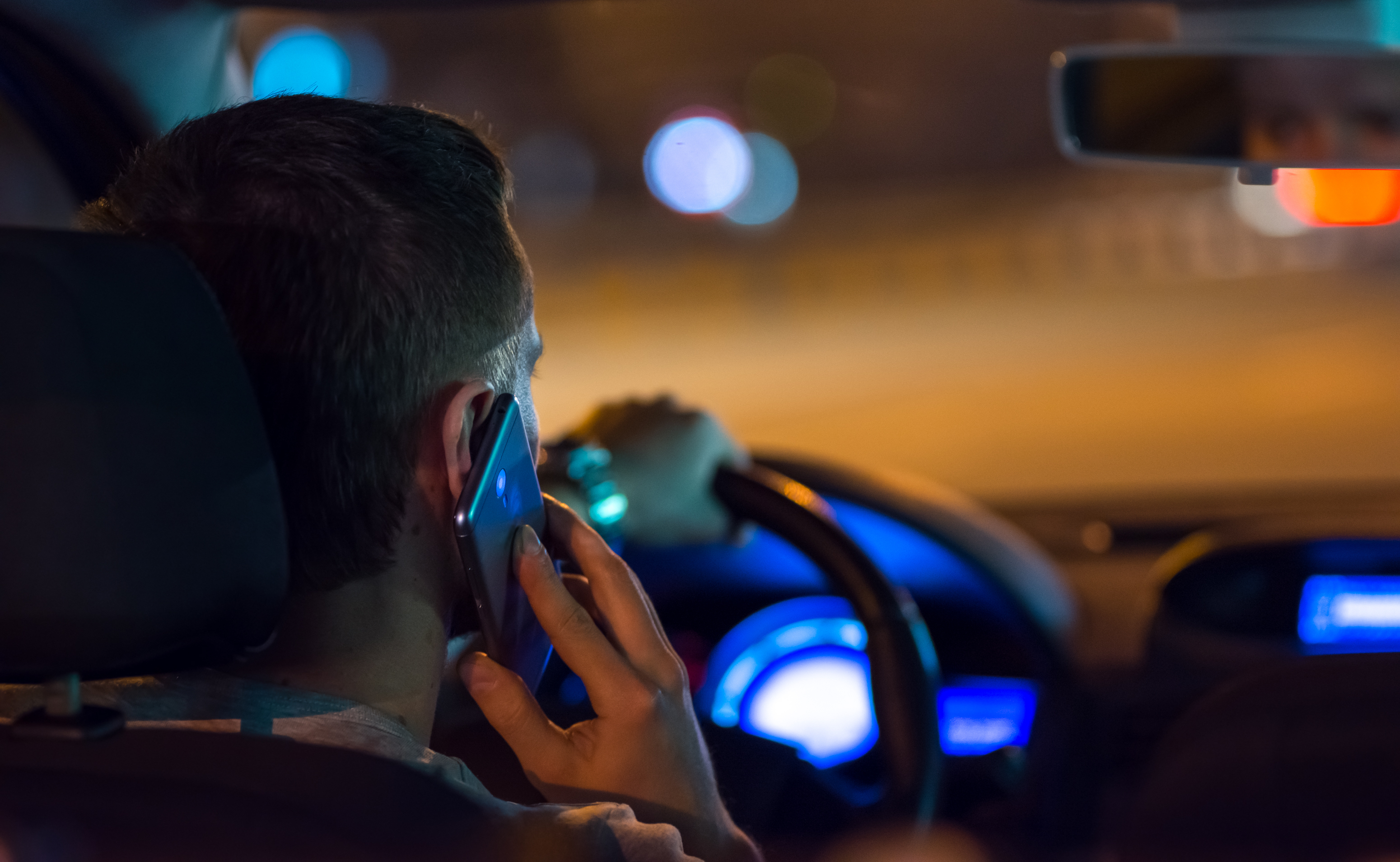 El hombre conduce un Automóvil por la ciudad y llama por teléfono. | Fuente: Shutterstock