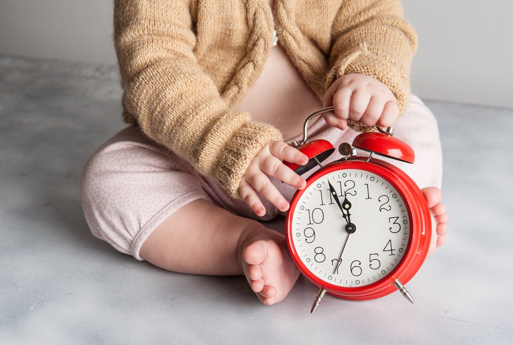 Bebé sosteniendo un reloj rojo. | Foto: Shutterstock