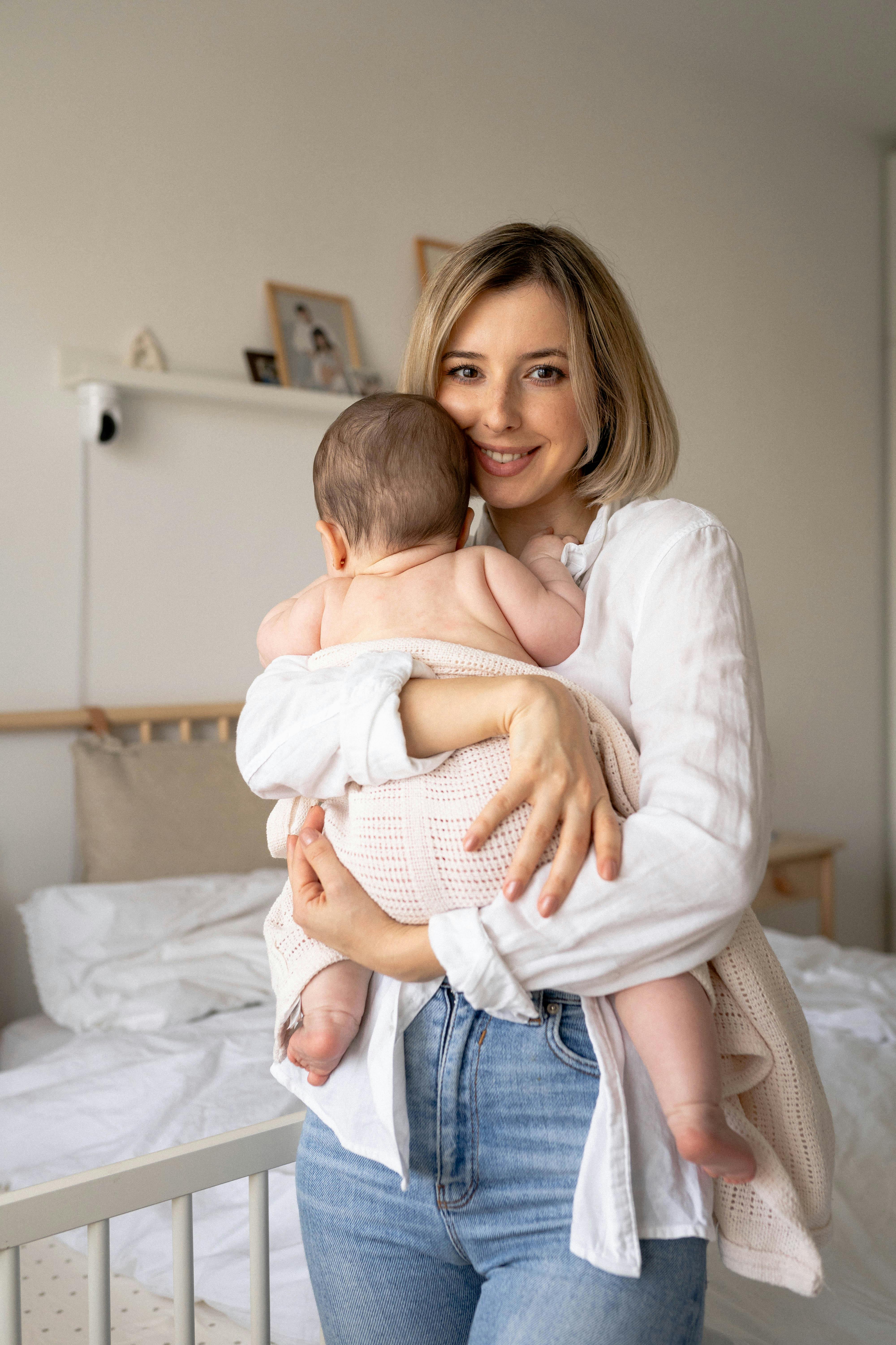 Una mujer feliz con su bebé en brazos | Fuente: Pexels