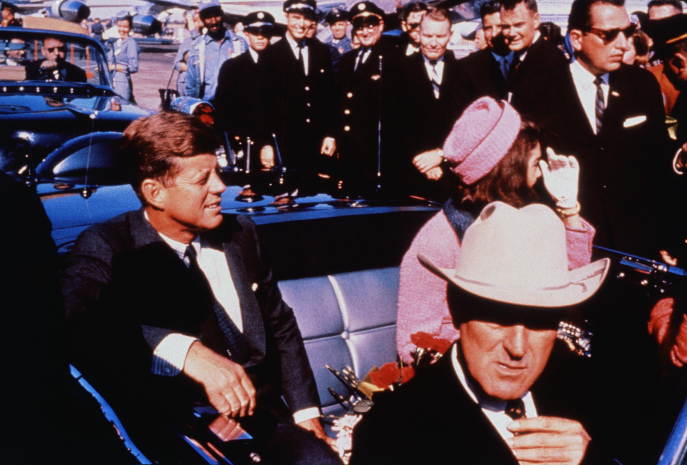 El gobernador de Texas John Connally se ajusta la corbata (en primer plano) mientras el presidente de EEUU John F Kennedy (izquierda) y la primera dama Jacqueline Kennedy (de rosa) se acomodan en los asientos traseros, el 22 de noviembre de 1963 | Fuente: Getty Images