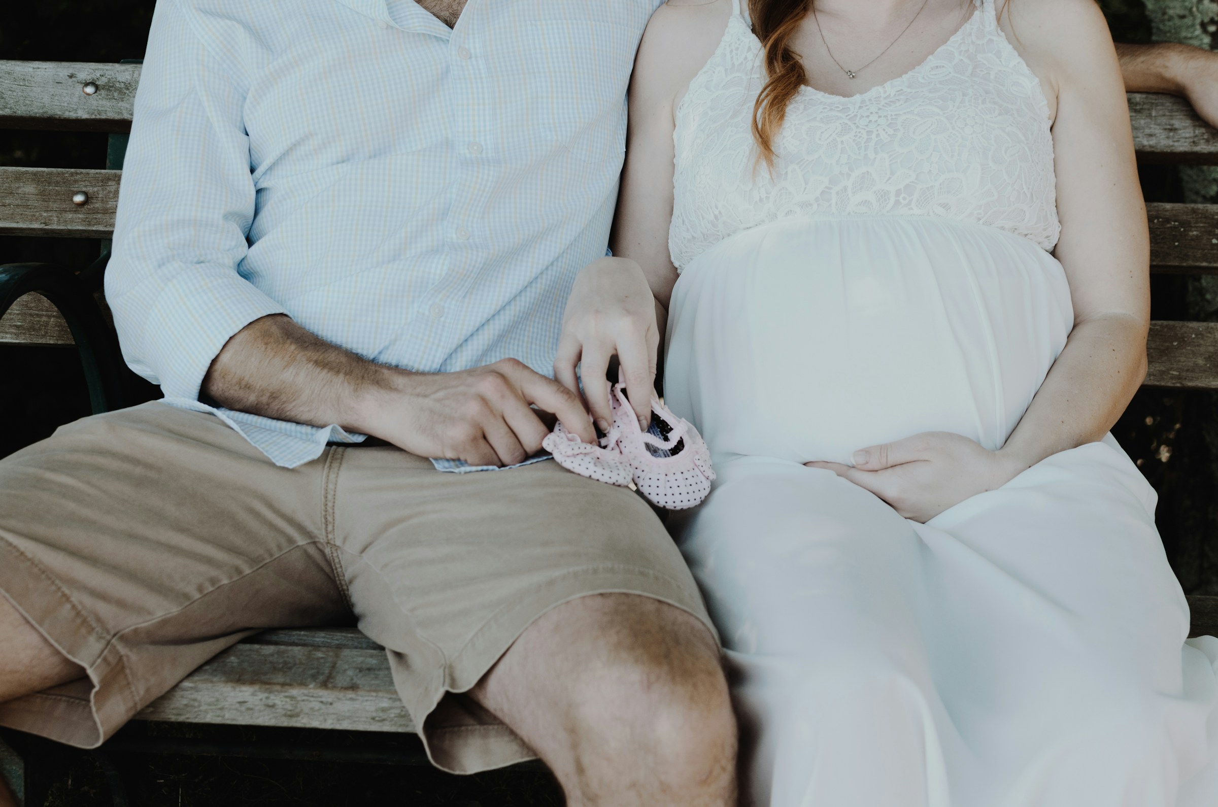 Una pareja embarazada sentada en un banco de madera | Fuente: Unsplash