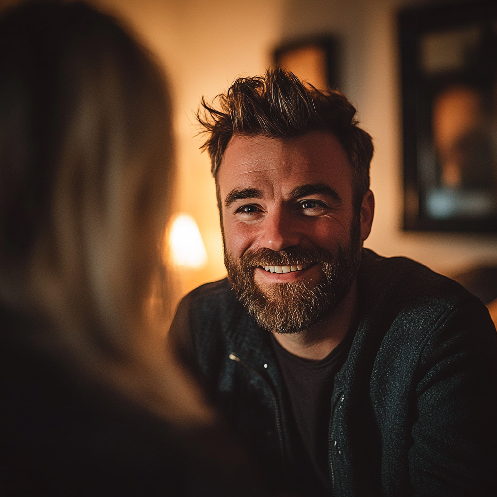 Un hombre sonriente hablando con una mujer en su salón | Fuente: Midjourney