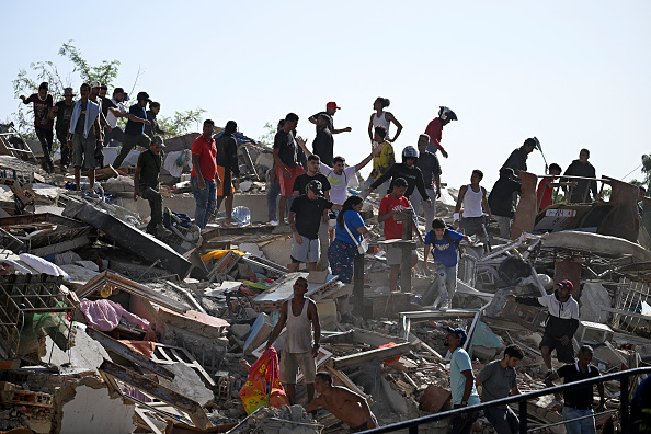Personas buscan sobrevivientes entre los escombros de un edificio colapsado, mientras otras intentan recuperar sus pertenencias, tras el terremoto ocurrido en Catia La Mar, estado La Guaira, a unos 30 kilómetros al noroeste de Caracas, el 25 de junio de 2026. Los dos sismos, los más fuertes registrados en Venezuela en más de un siglo, dejaron al menos 164 muertos y destruyeron numerosos edificios cerca de la capital, donde los habitantes continuaban buscando a sus familiares desaparecidos.
