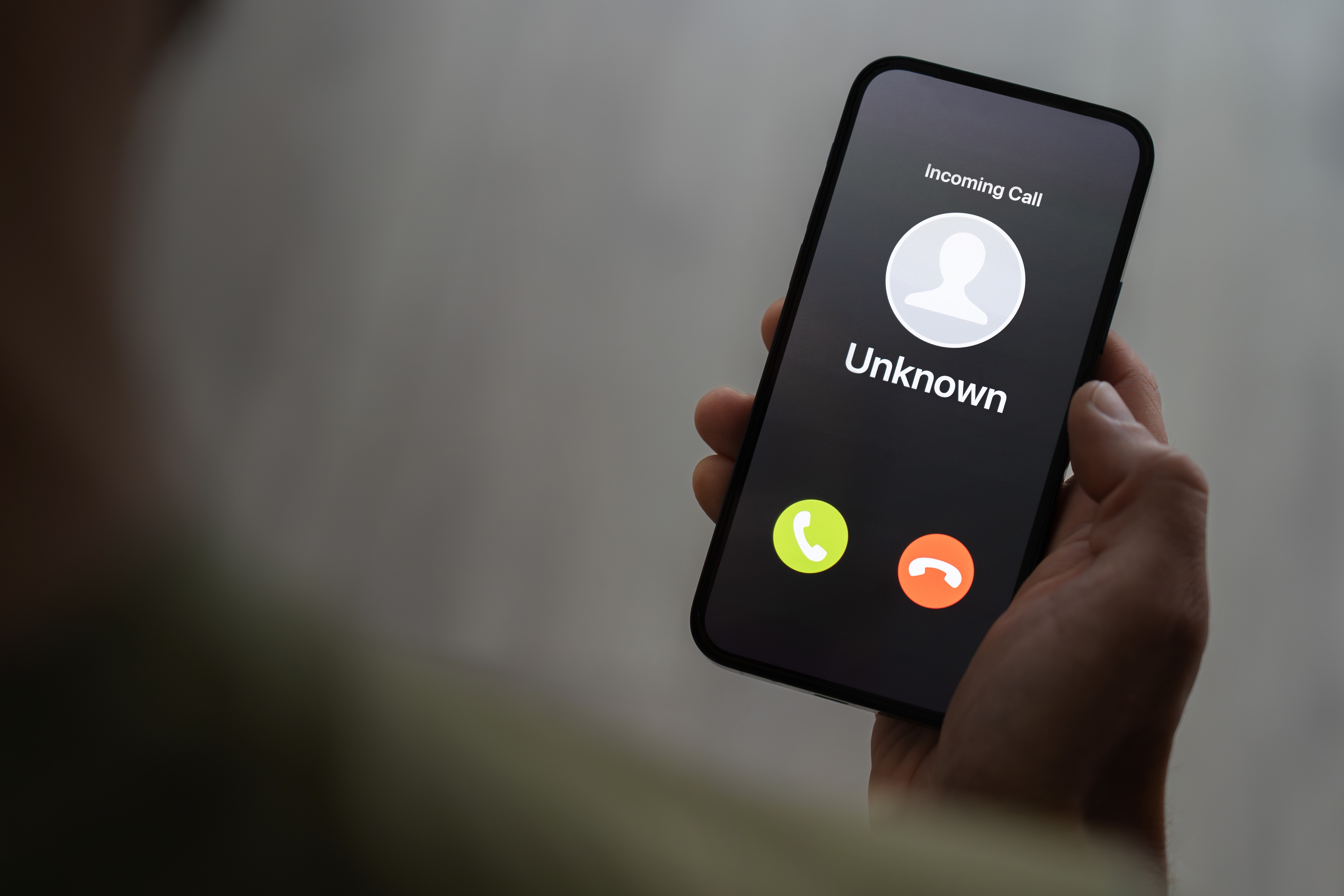 Persona sosteniendo un teléfono con llamada desconocida. | Fuente: Shutterstock
