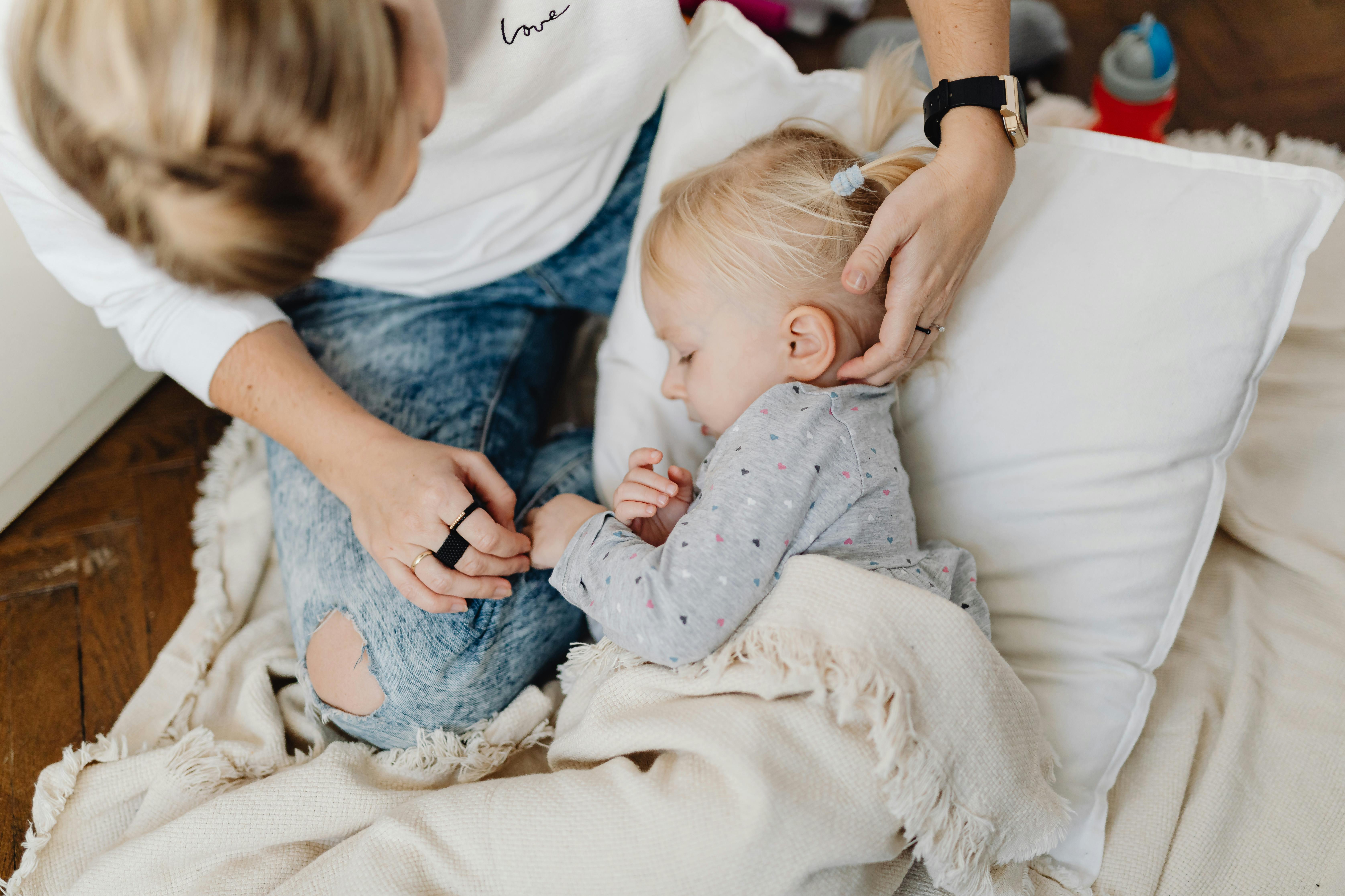 Mujer arropando a su hija en la cama | Fuente: Pexels