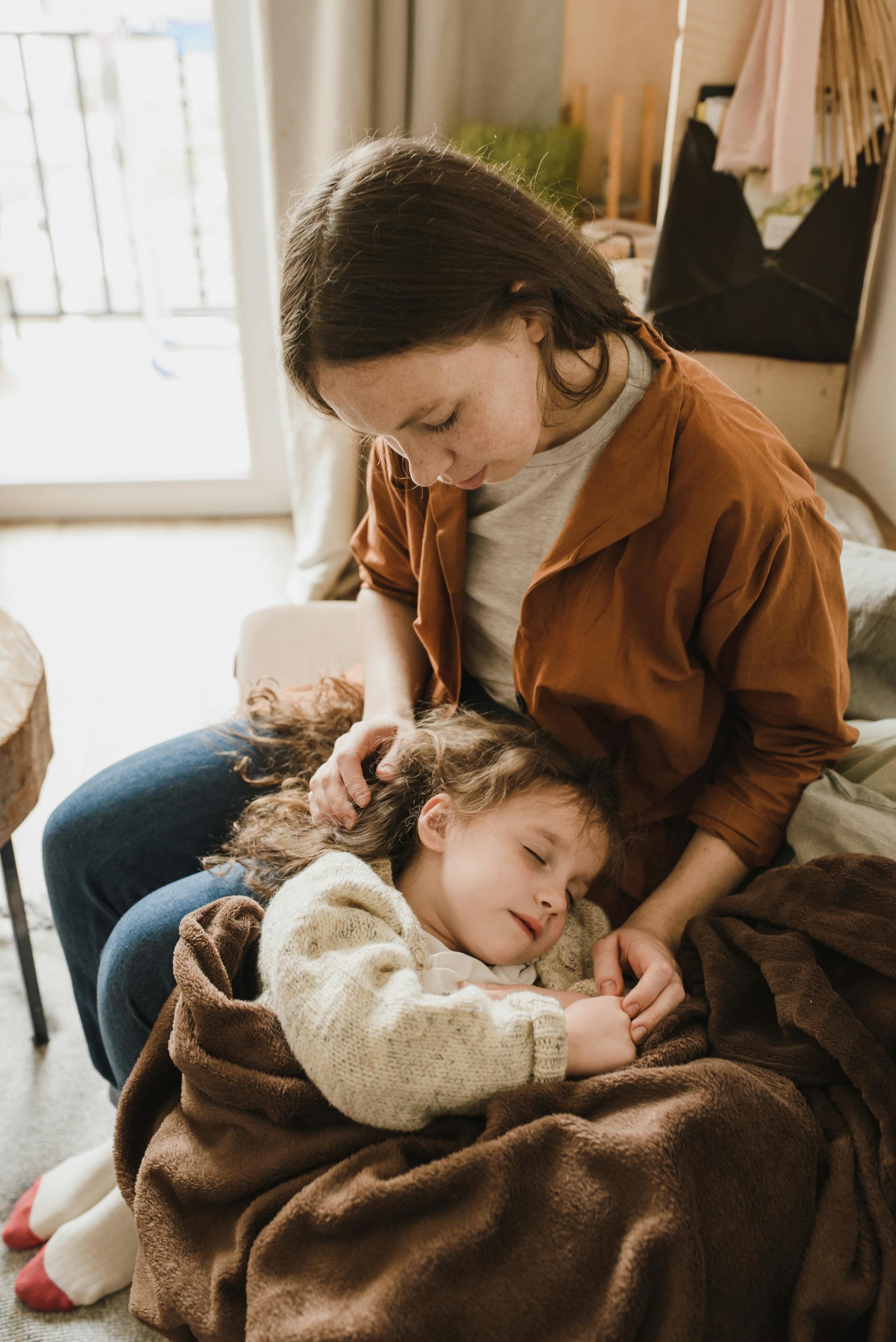 Una niña durmiendo en el regazo de su madre | Fuente: Pexels