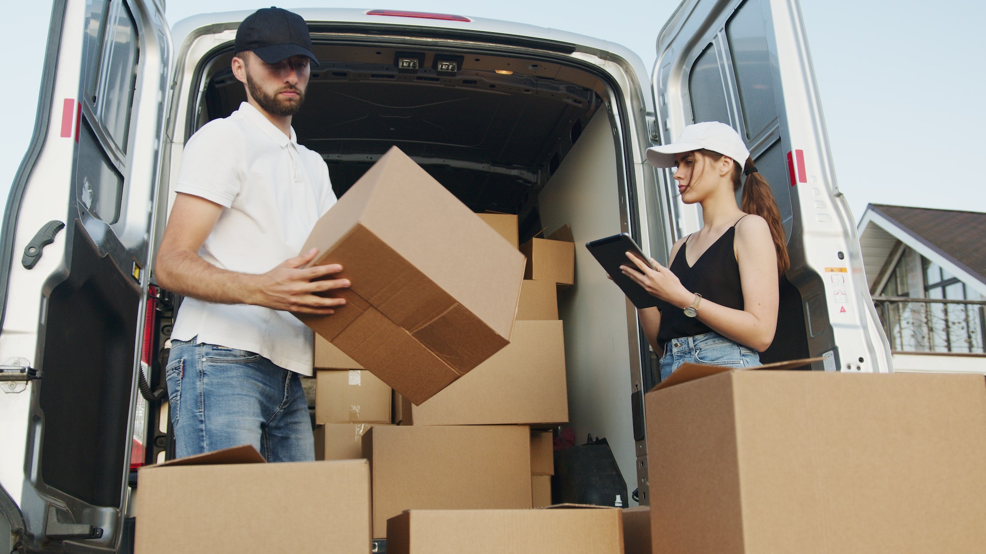 Dos personas cargando cajas en un vehículo | Fuente: Pexels