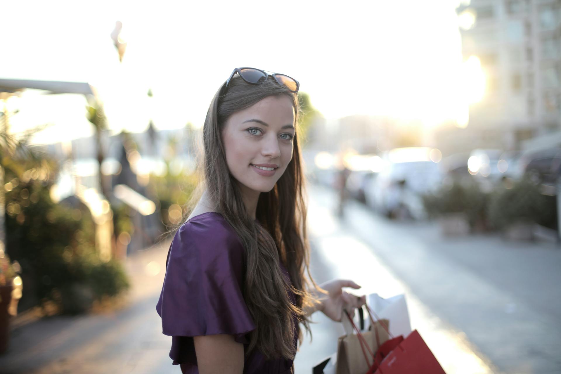 Una mujer con las bolsas de la compra en la mano y sonriendo | Fuente: Pexels