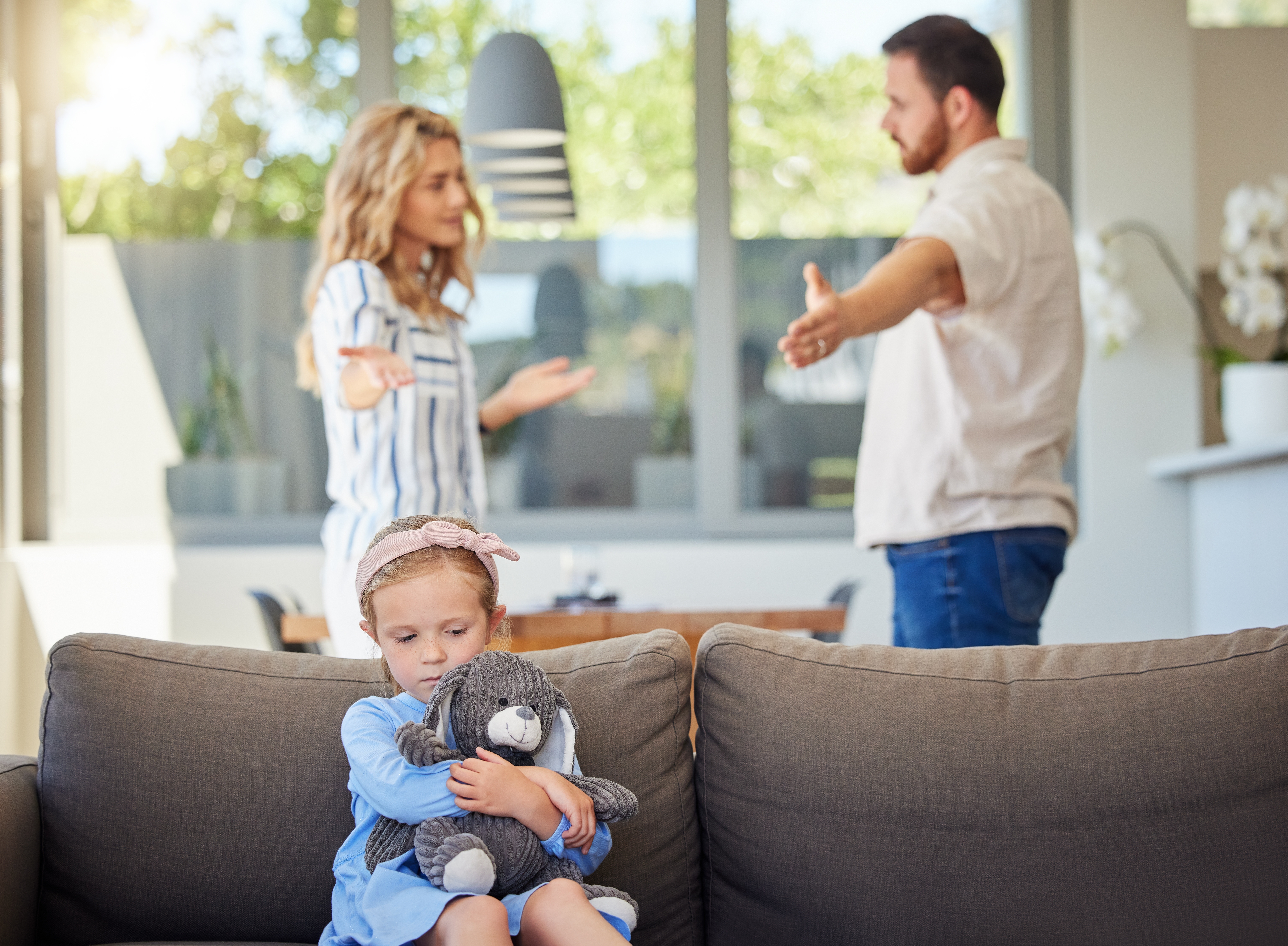 Una niña asustada que oye discutir a sus padres de fondo | Fuente: Shutterstock