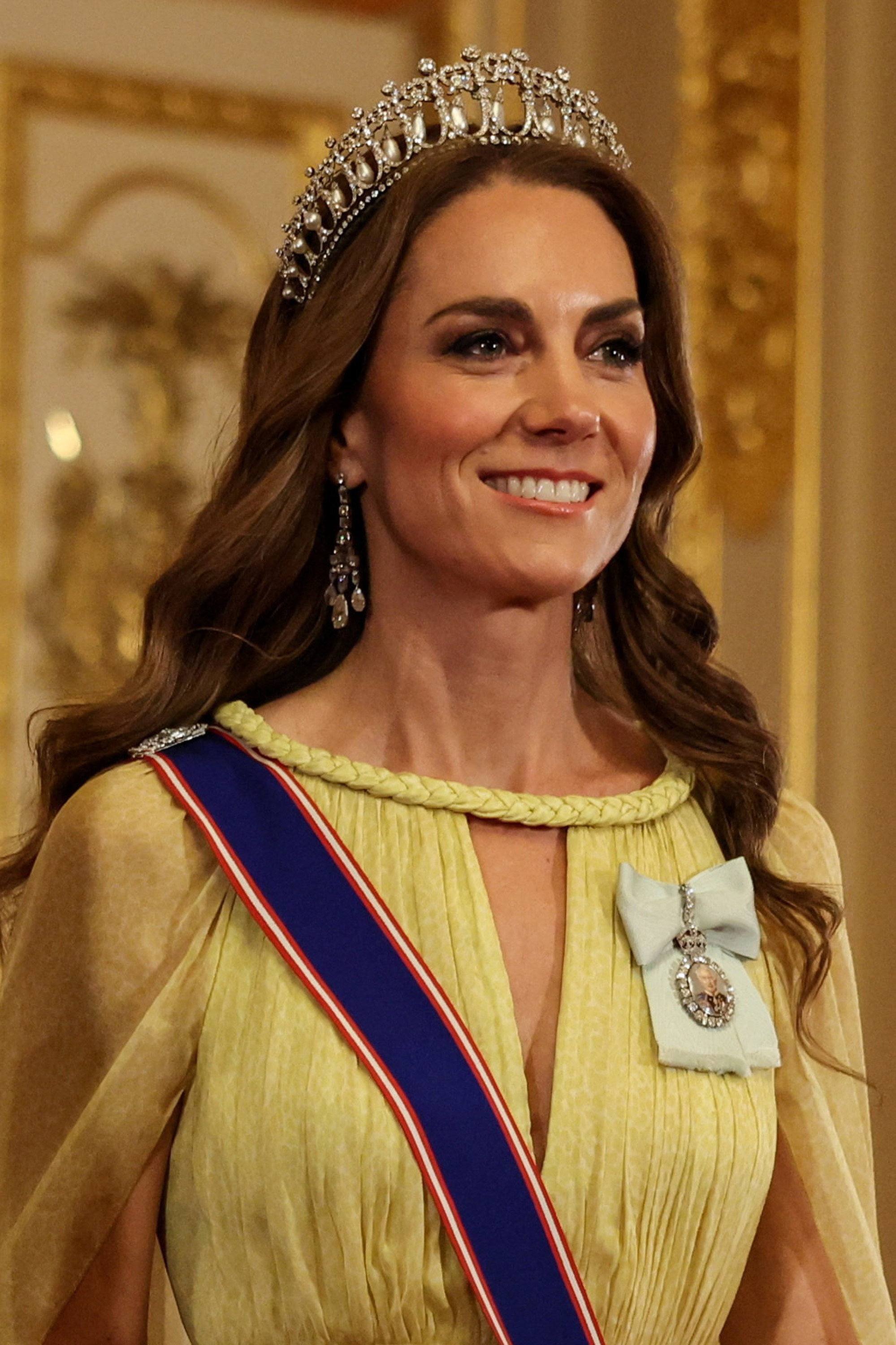 Un primer plano muestra las magníficas joyas reales que luce Catherine, princesa de Gales, durante los festejos del 20 de octubre de 2026. Sobre su cabello ondulado lleva la tiara Lover's Knot de la reina Mary y pendientes de perlas de la reina Elizabeth II. Junto al cuello trenzado del vestido luce una miniatura con el retrato del rey Charles III, perteneciente a la Orden de la Familia Real, sobre un lazo de seda azul claro. | Fuente: Getty Images
