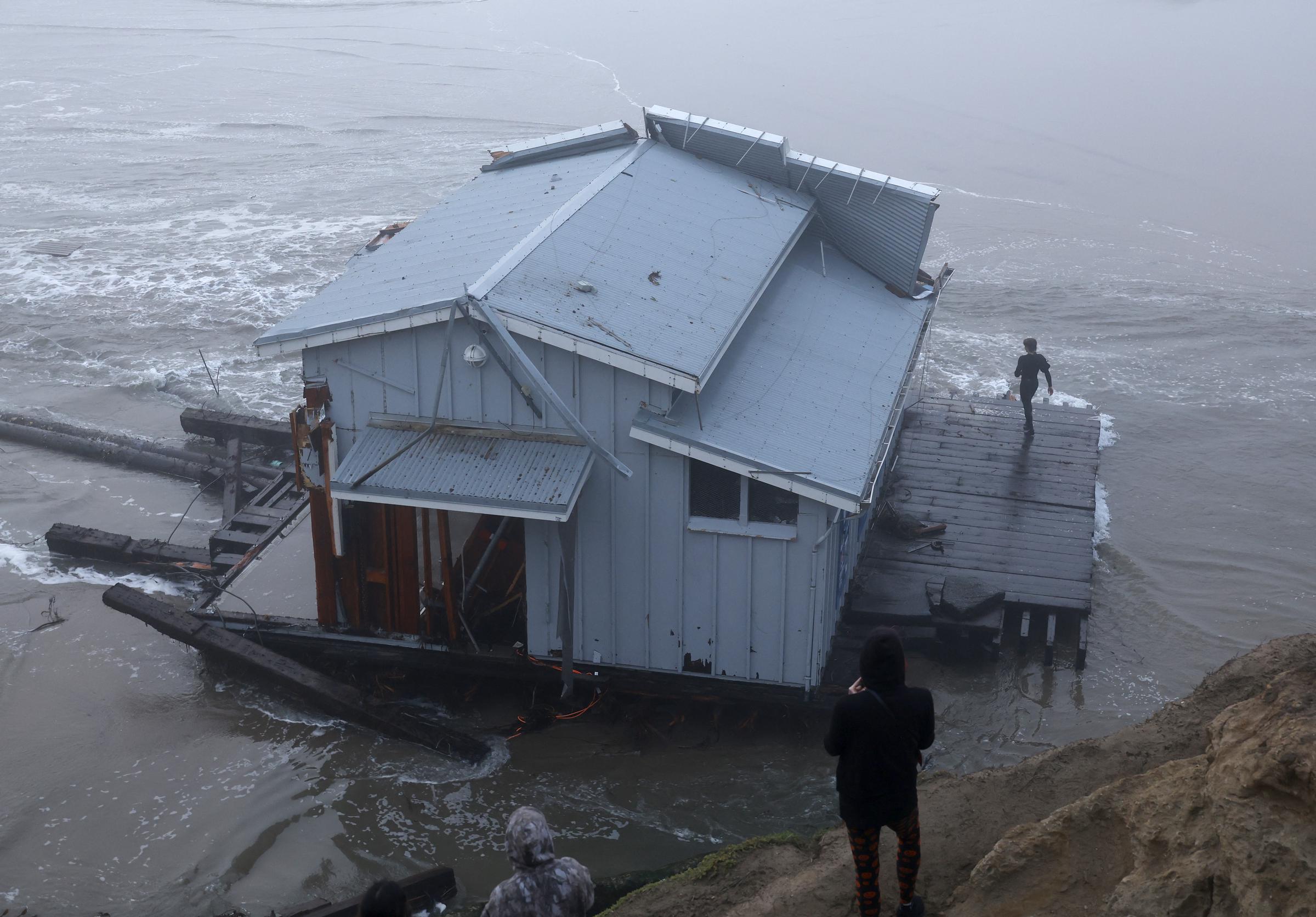 Un grupo de personas observa el muelle derrumbado en el embarcadero de Santa Cruz, California, el 23 de diciembre de 2024 | Fuente: Getty Images