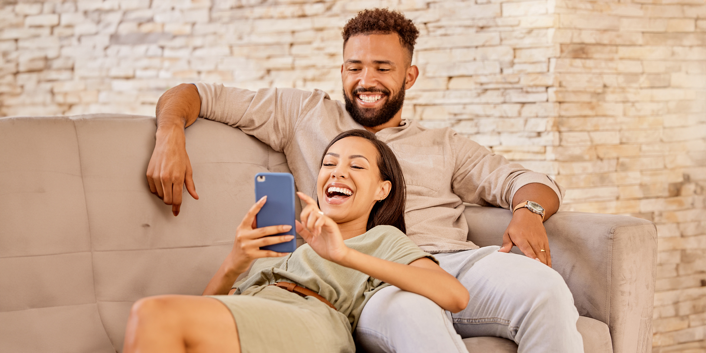 Una pareja riendo mientras mira la pantalla de un teléfono | Fuente: Shutterstock