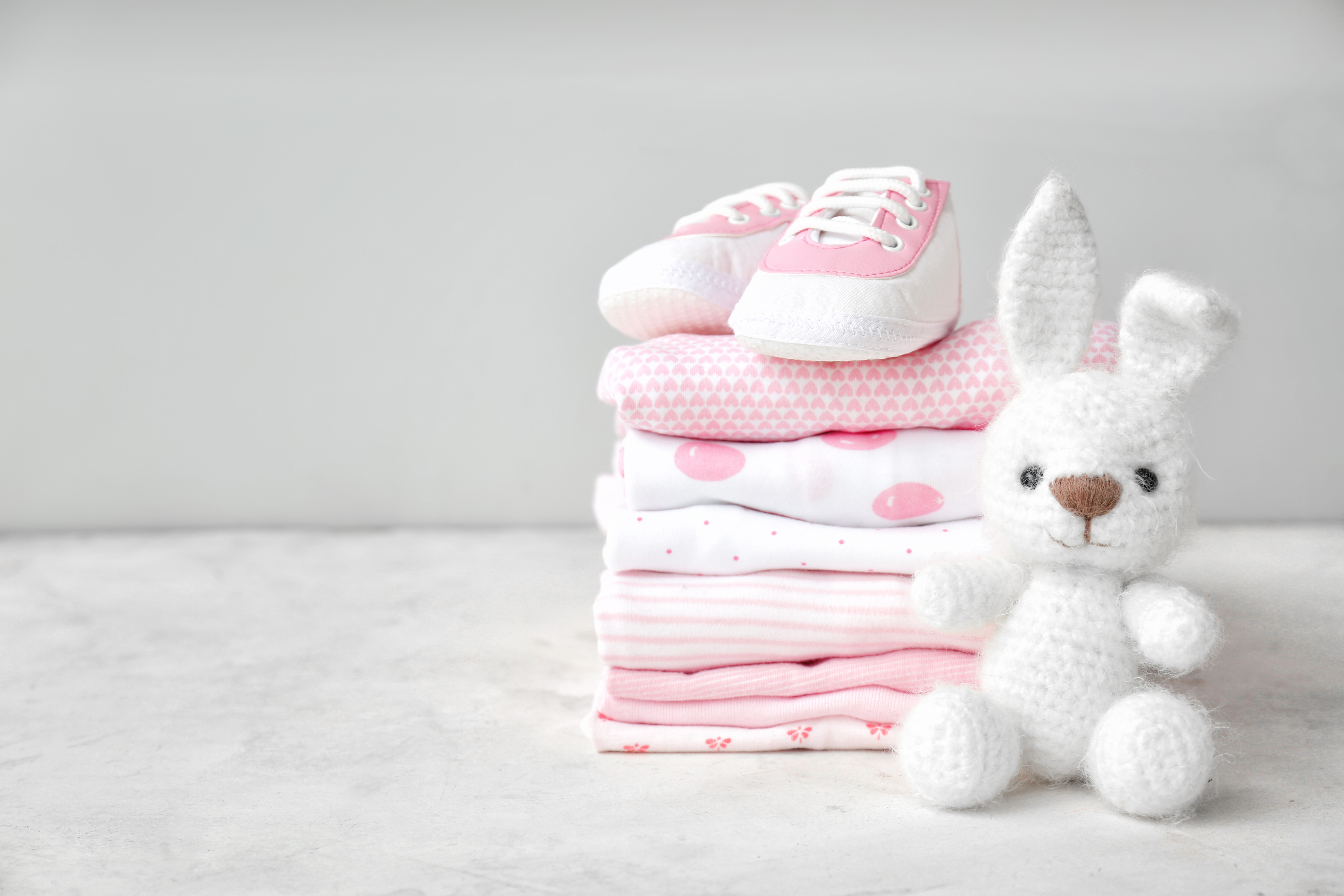Una pila de ropa de bebé, zapatos y un juguete sobre una mesa. | Foto: Shutterstock