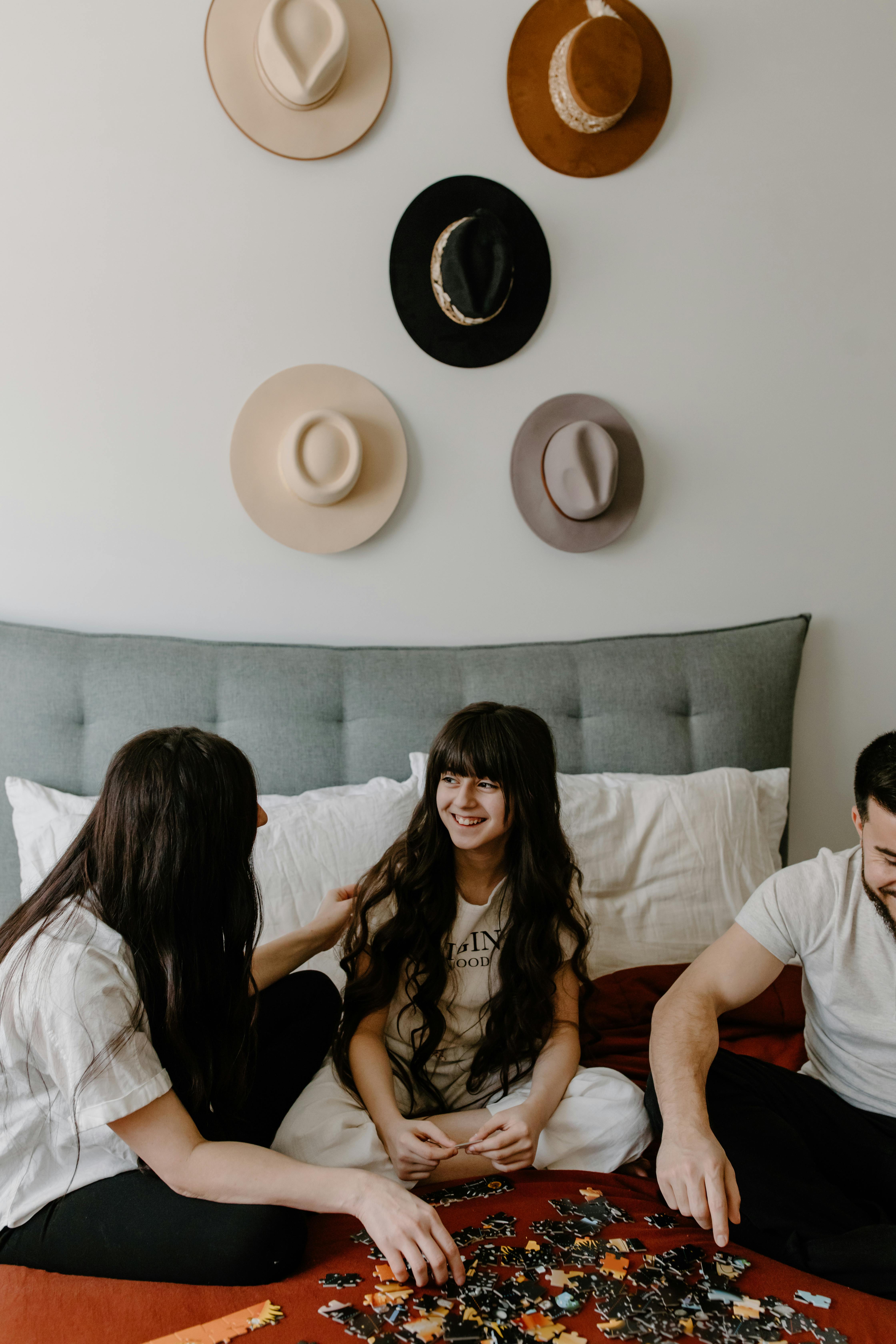 Una familia feliz formada por un padre, una niña y una madre construyendo juntos un puzzle | Fuente: Pexels