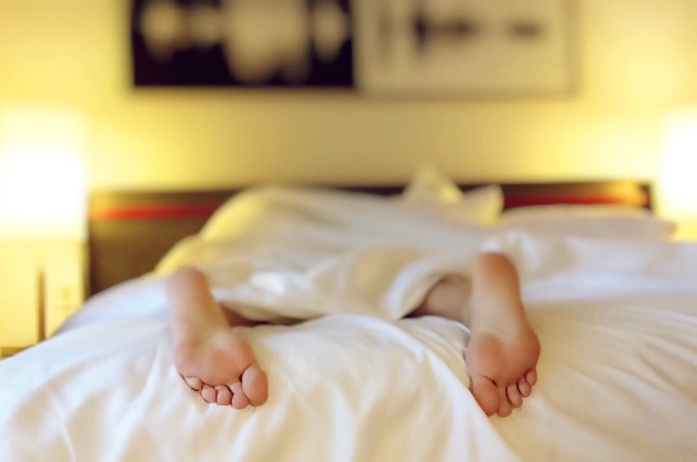 Pies de una persona acostada en la cama. | Foto: Pexels