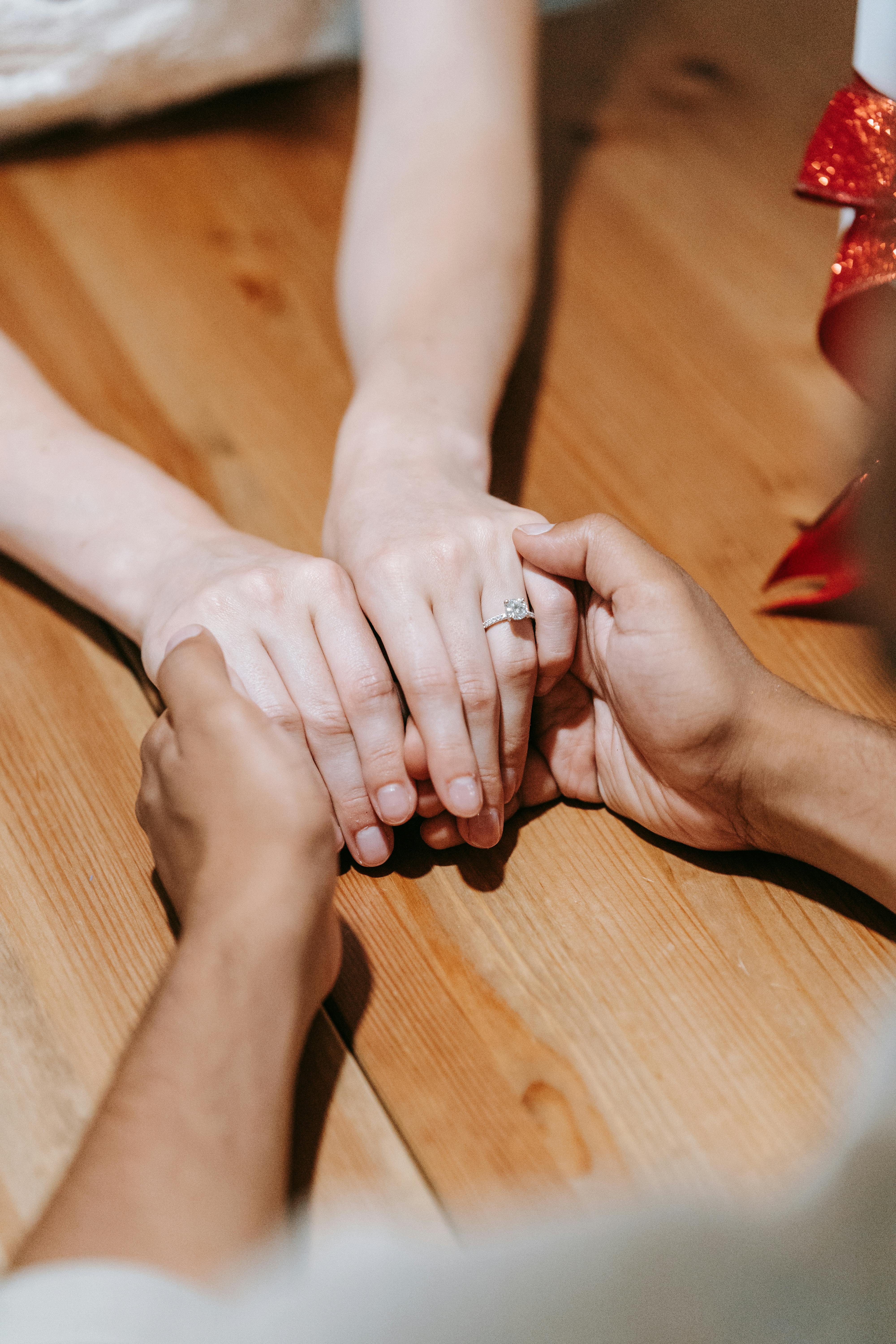 Una pareja cogida de la mano sobre una mesa | Fuente: Pexels