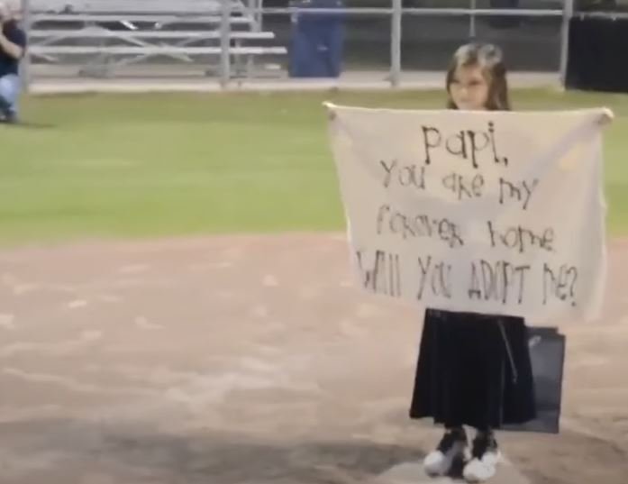 Alessandra sosteniendo el cartel en el campo de béisbol. | Foto: Youtube/WVTM 13 News