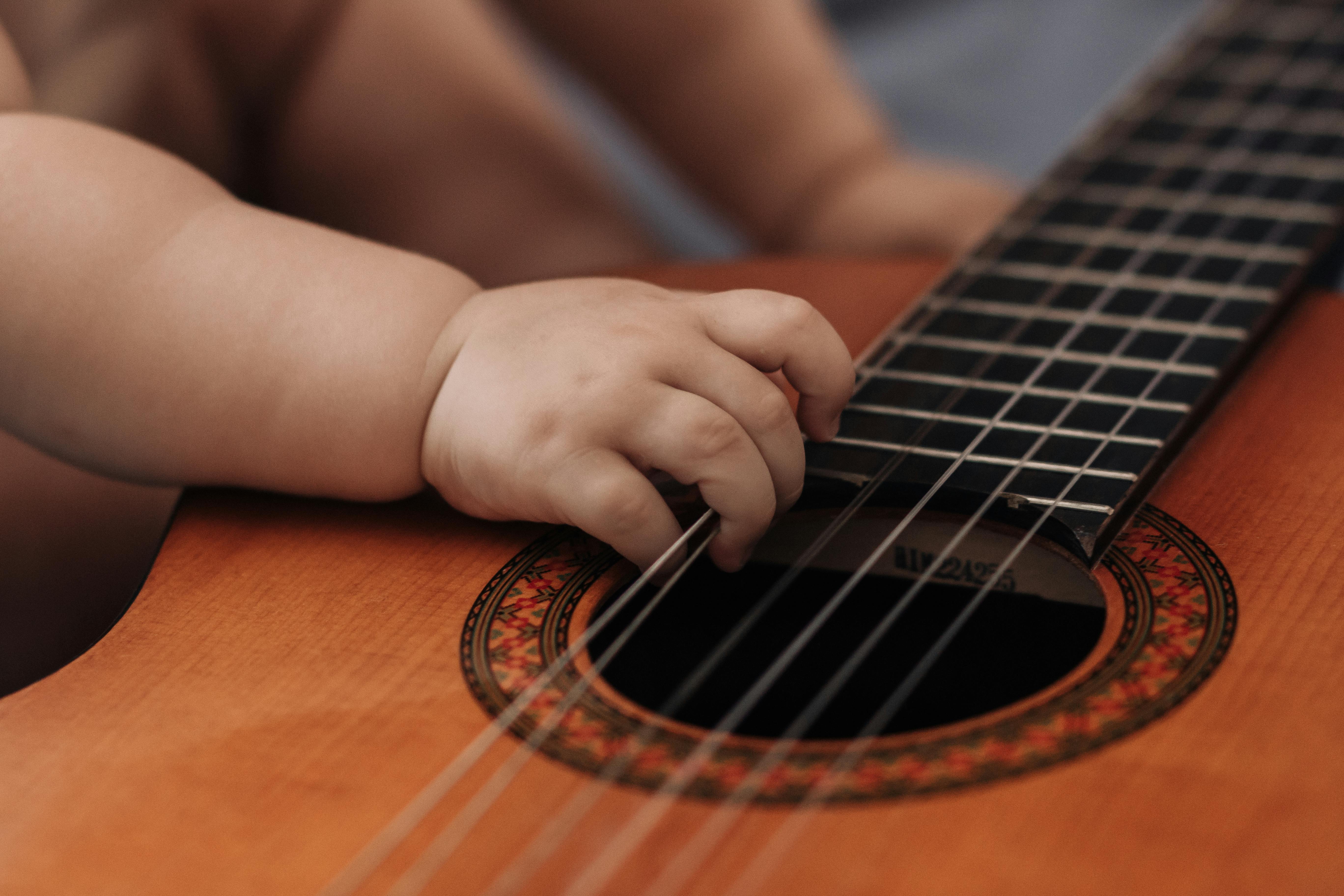 La mano de un bebé sujetando las cuerdas de una guitarra | Fuente: Pexels