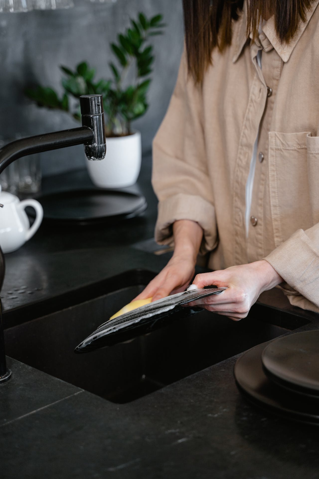 Una mujer fregando platos en la cocina | Fuente: Pexels