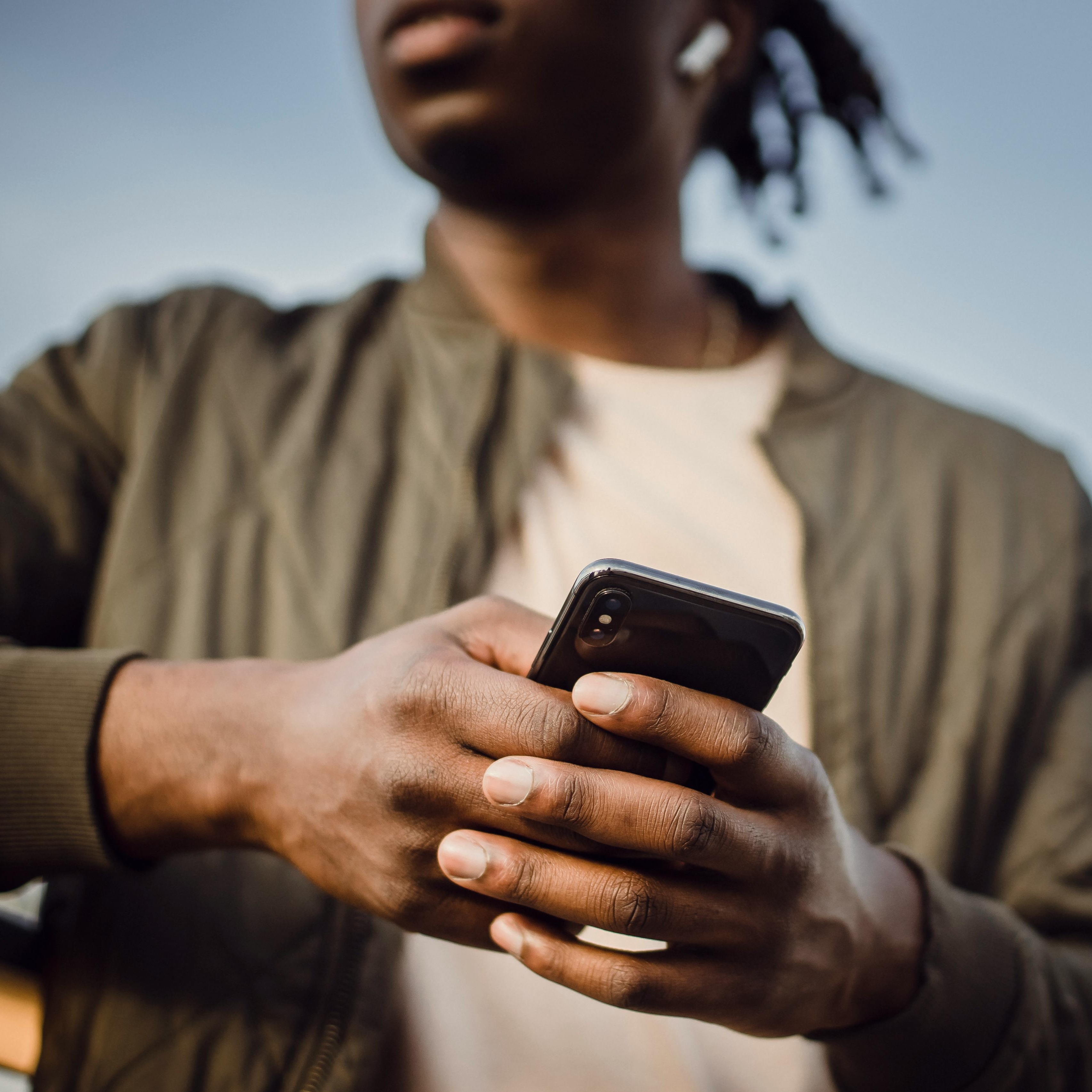 Un hombre haciendo una llamada de móvil con auriculares | Fuente: Pexels