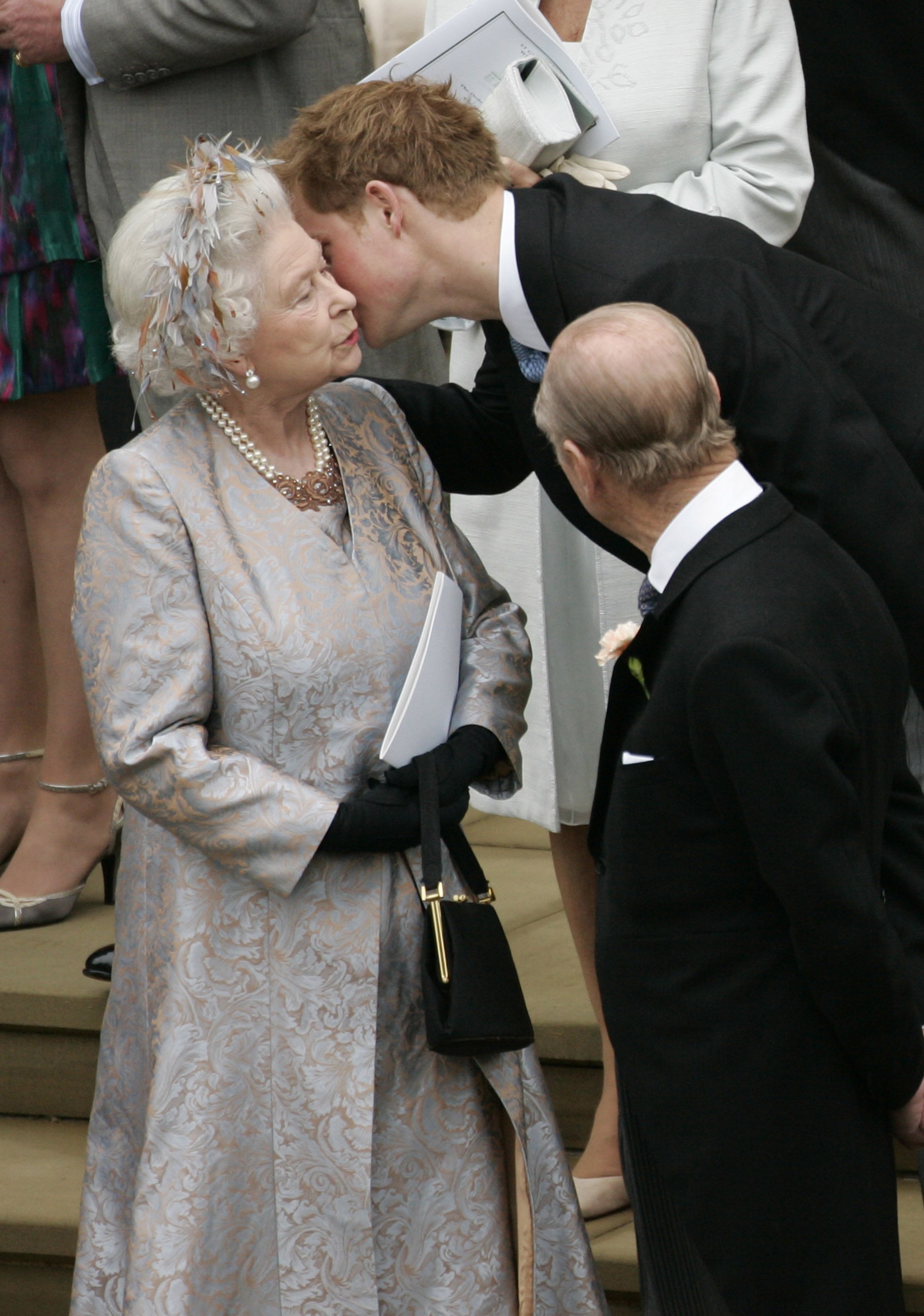 El príncipe Harry besando a su abuela, la reina Elizabeth II, después de la boda de Peter Phillips con Autumn Kelly, en la Capilla de St. George en el castillo de Windsor, el 17 de mayo de 2008 en Windsor, Inglaterra. | Foto: Getty Images