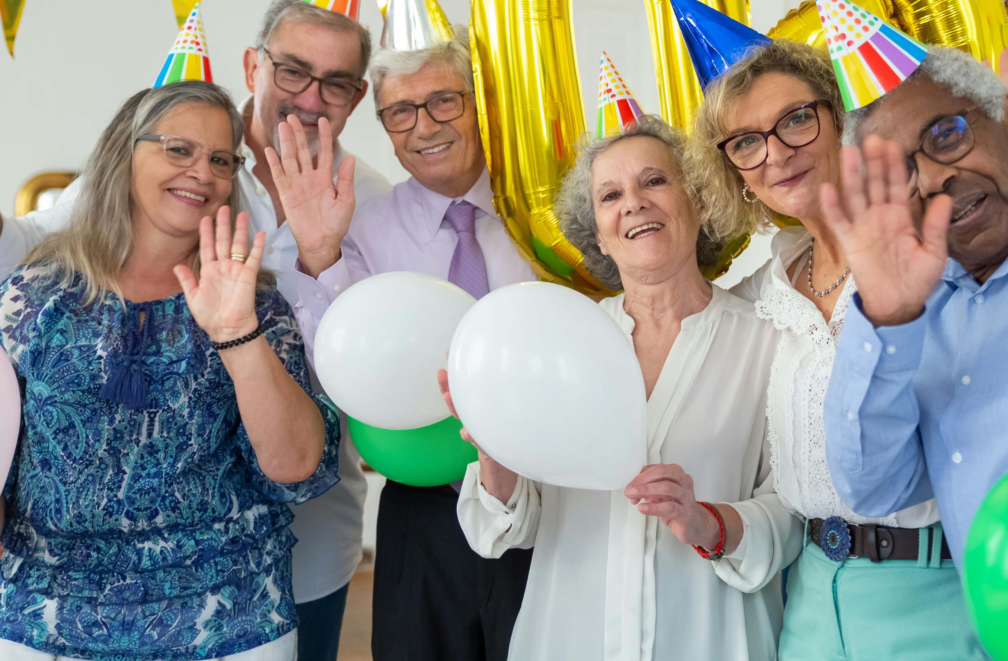 Gente con sombreros de fiesta y globos en las manos | Fuente: Pexels