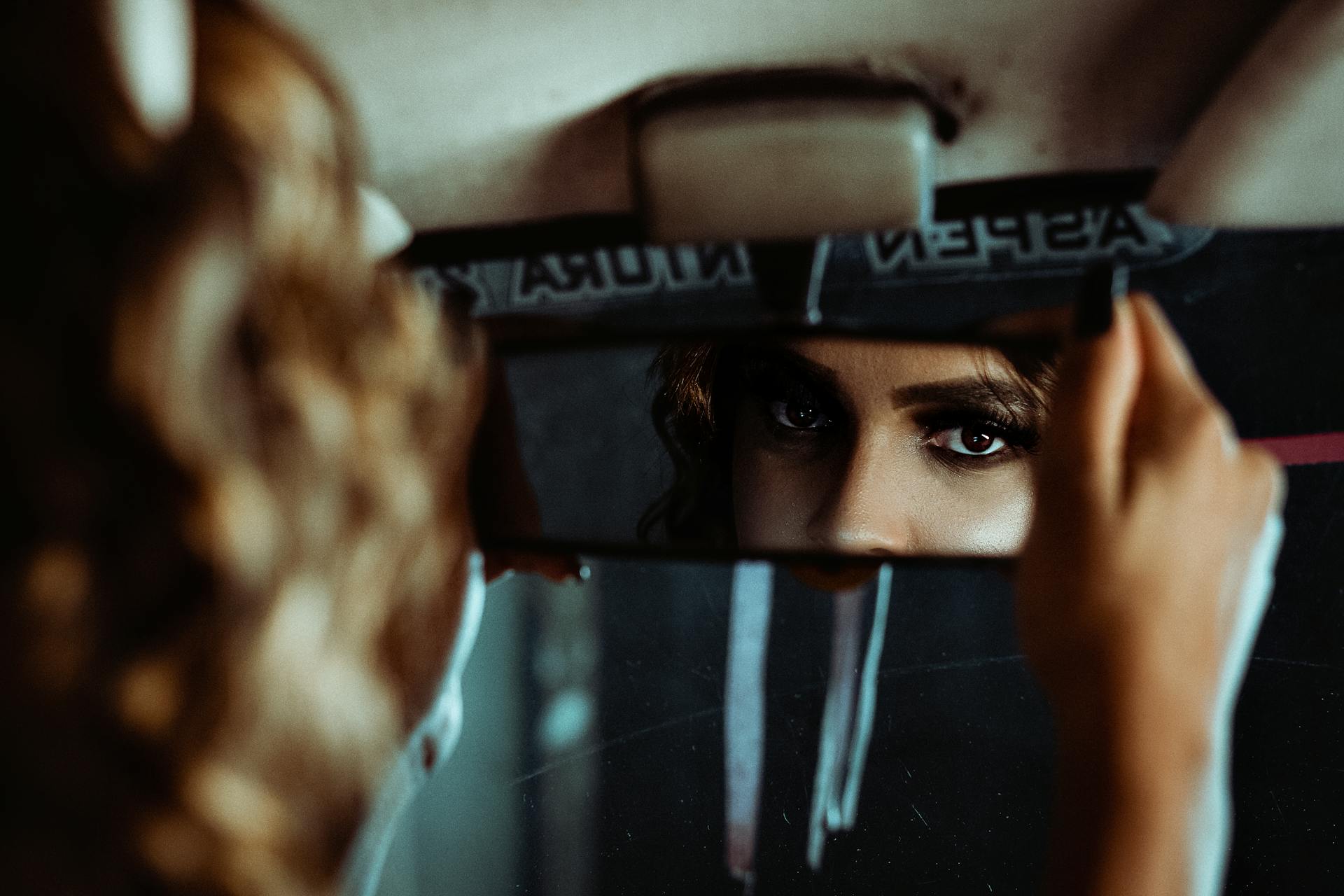 Una mujer ajustando el espejo retrovisor | Fuente: Pexels