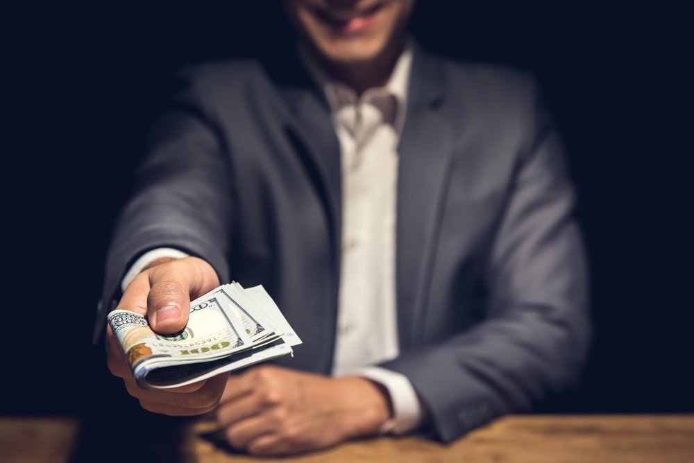 Hombre entrega dinero. || Fuente: Shutterstock