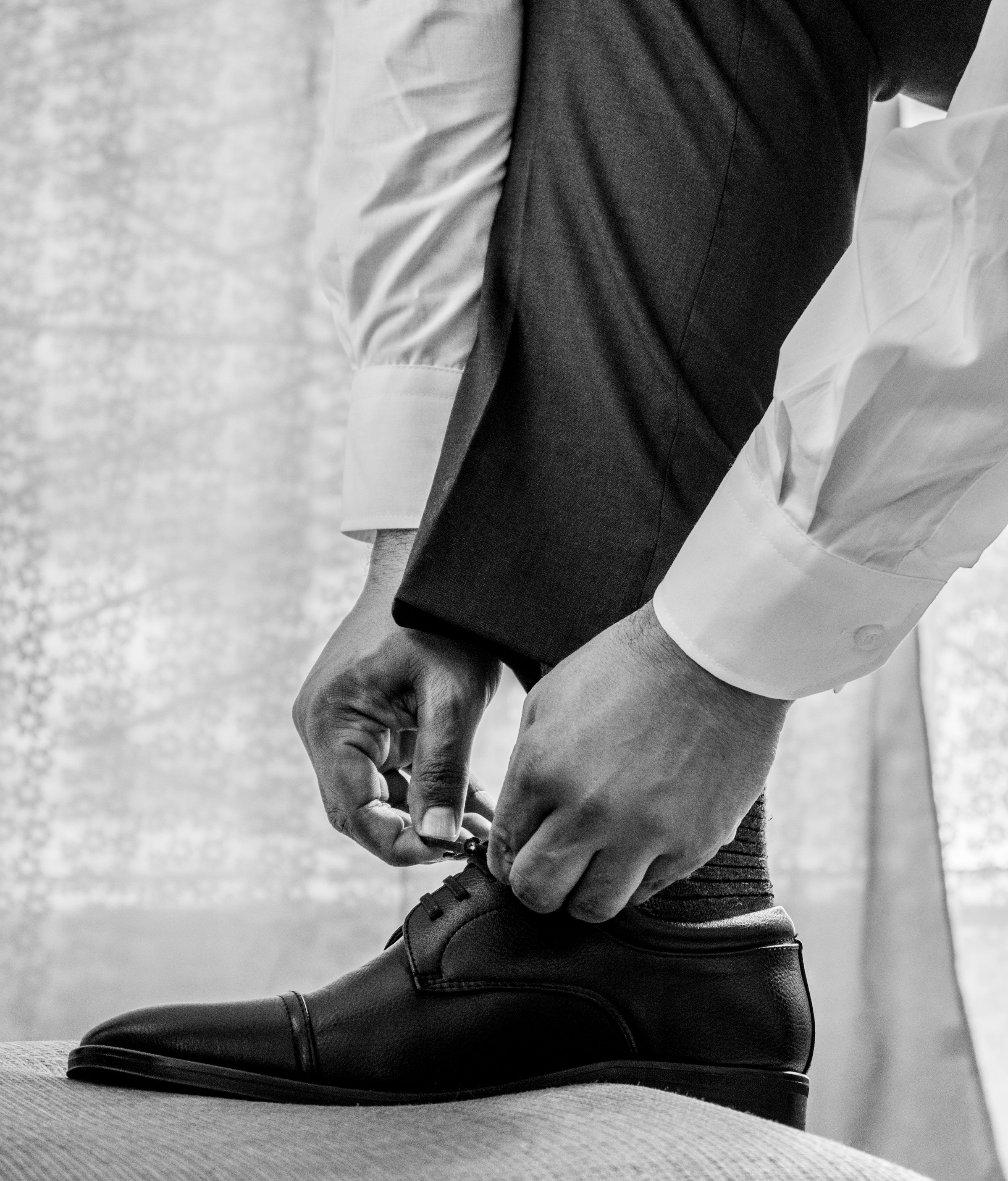 Primer plano extremo de un hombre con camisa de vestir blanca y pantalones negros que lleva zapatos de cuero negros | Fuente: Unsplash