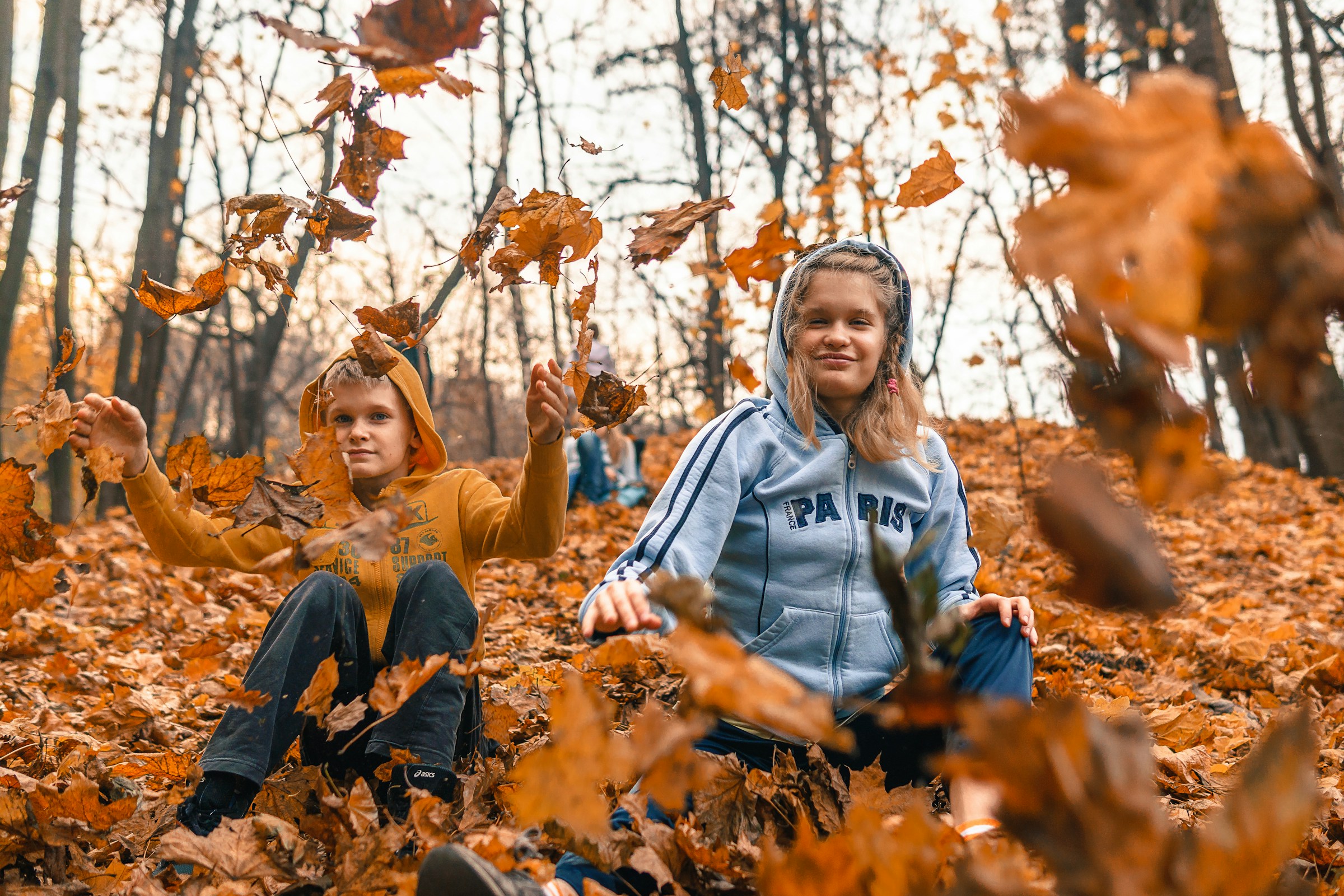 Dos niños jugando entre hojas caídas | Fuente: Unsplash