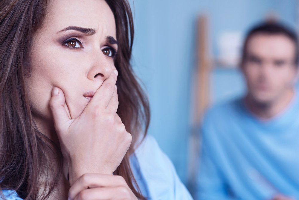 Mujer deprimida reflexionando con su pareja de fondo. | Foto: Shutterstock