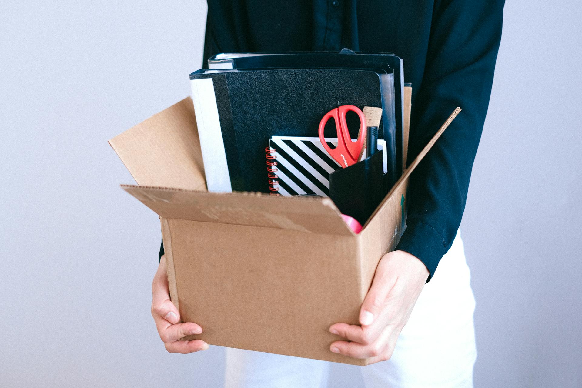 Una mujer sostiene una caja de cartón con sus artículos de oficina dentro | Fuente: Pexels