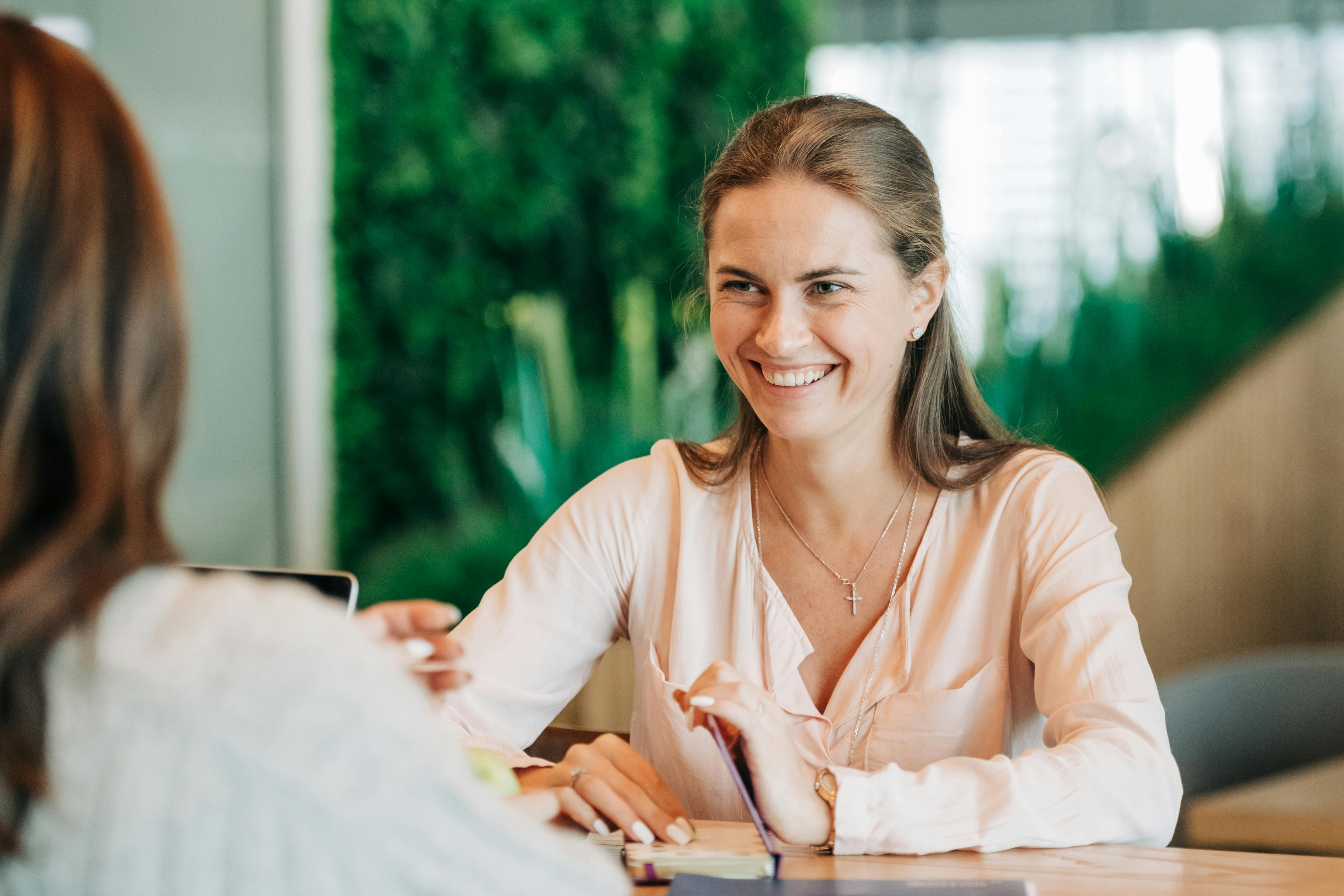 Una mujer sonriente charlando con su colega | Fuente: Pexels