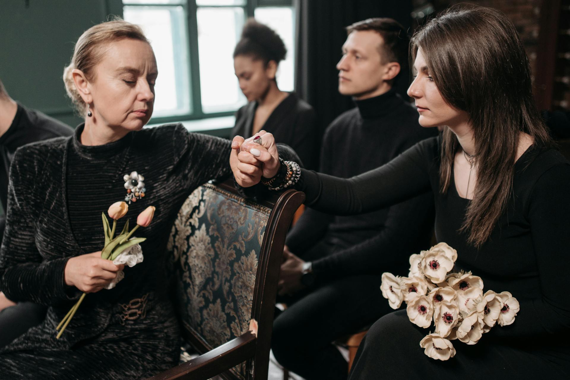 Due donne che si tengono per mano mentre partecipano a un funerale | Fonte: Pexels